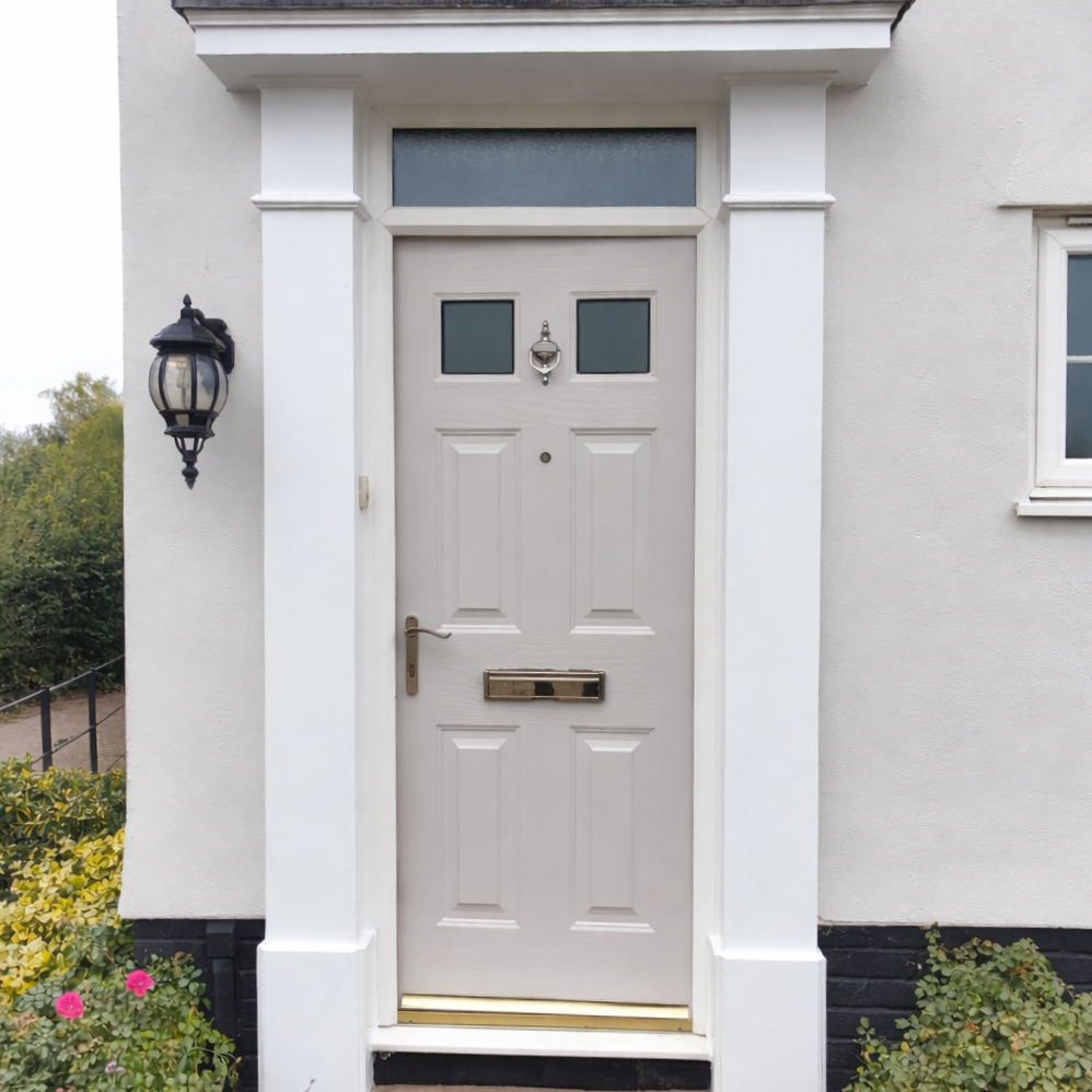 White front door with small windows, mail slot, handle, and doorbell, surrounded by white walls and outdoor plants, with a black lamp fixture on the left side.