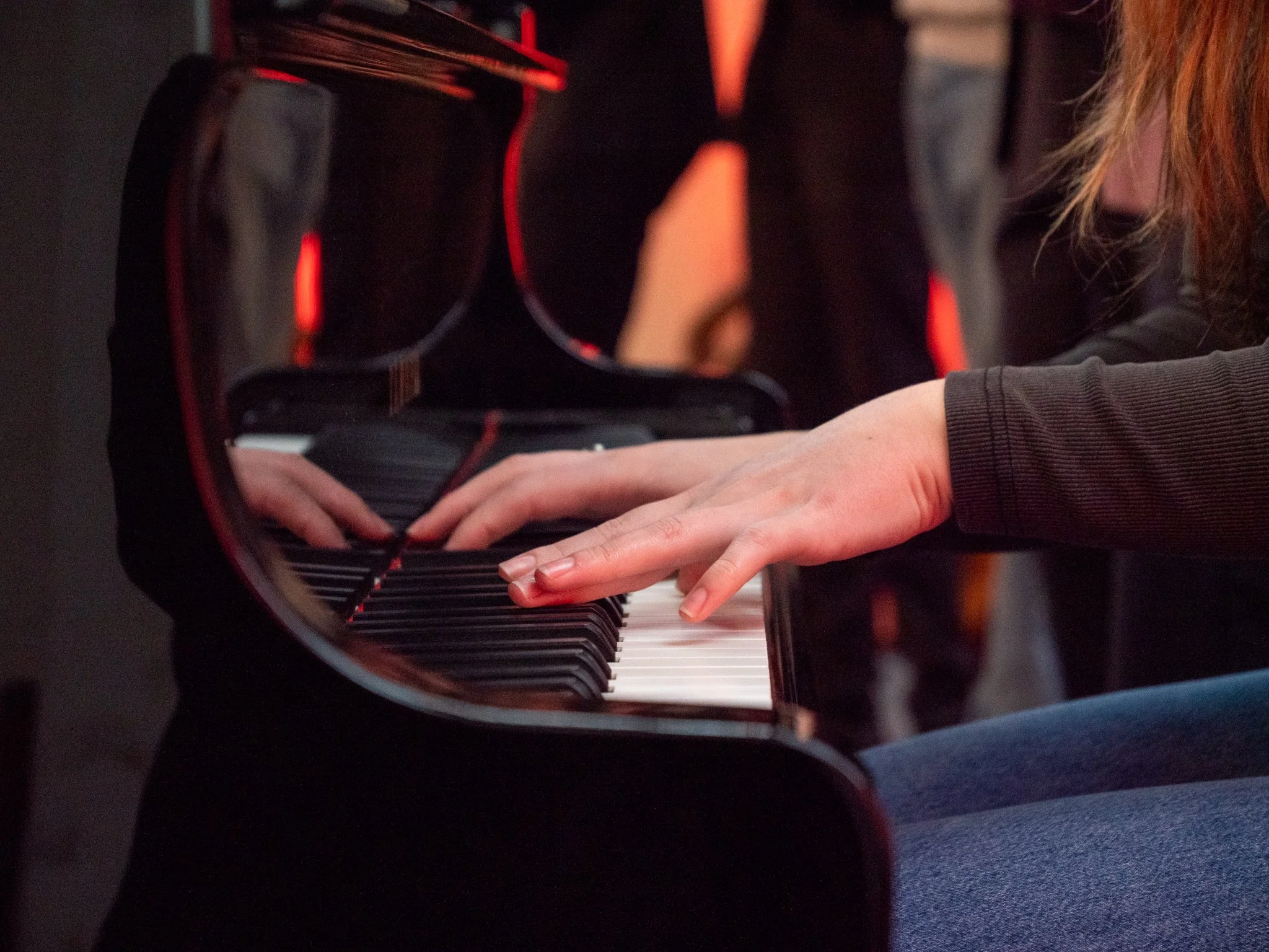 Persoon die op een piano speelt in een donkere zaal.