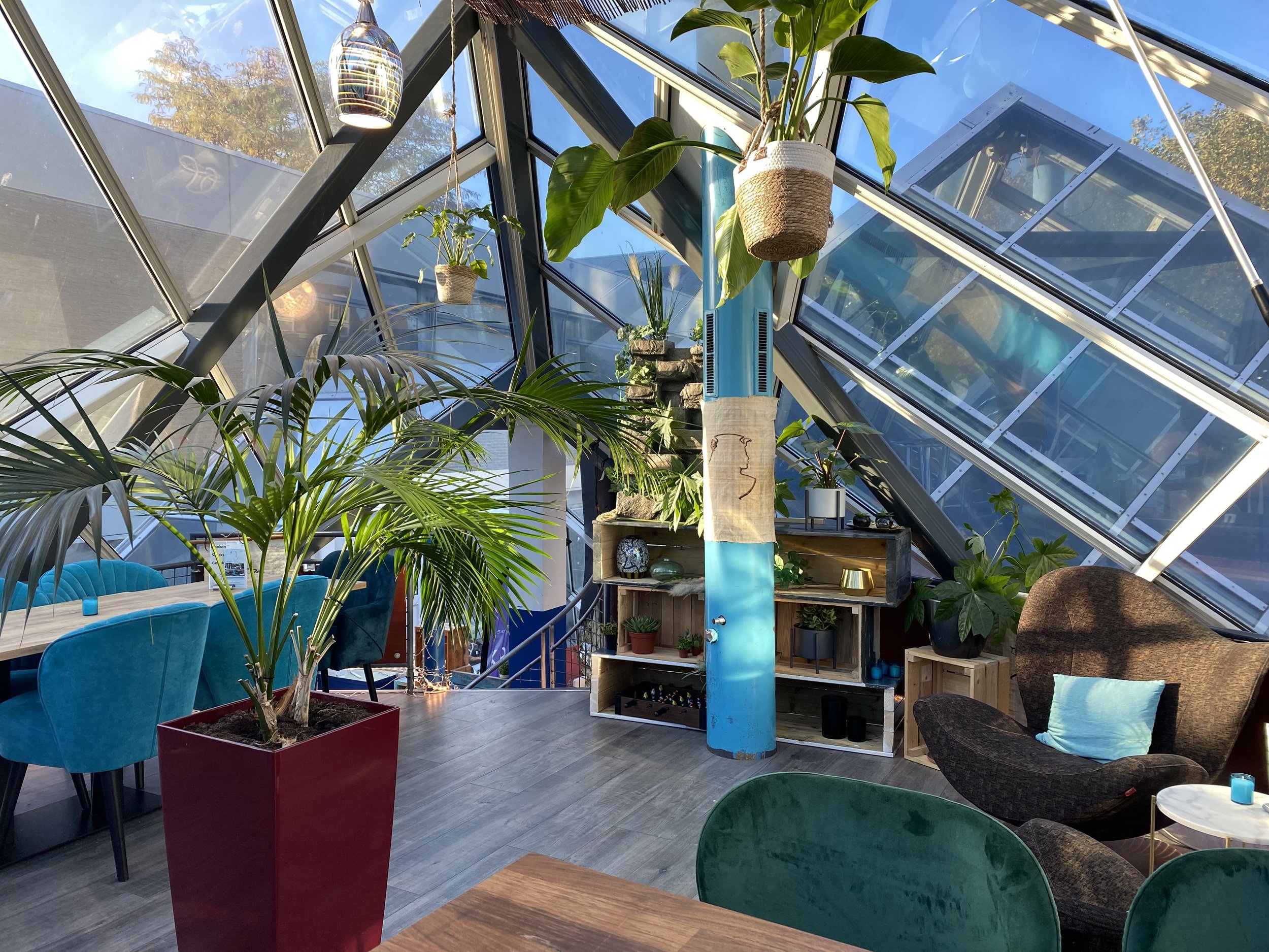 De bovenverdieping van De Serre van Cleopatra in Wageningen, met planten en kleurrijke zitmeubels.