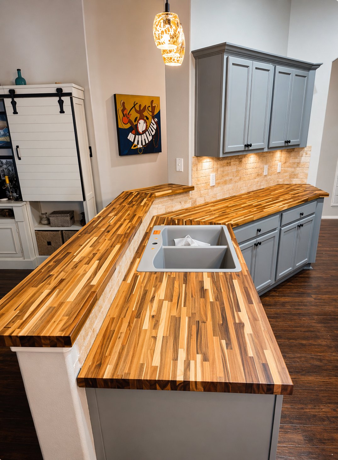 Kitchen with wooden countertops, gray cabinets, a painted artwork of a deer playing a keyboard, and a ceiling light fixture.