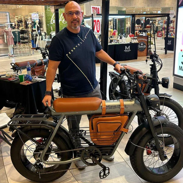 Man standing next to an electric bicycle inside a shopping mall.