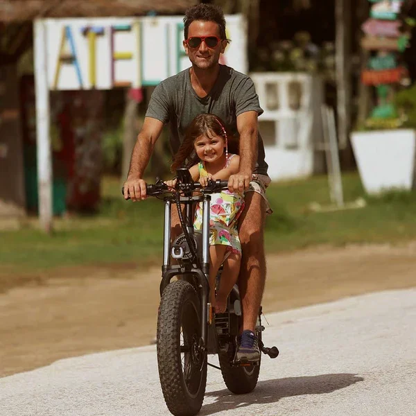 A man and a young girl riding a bicycle together on a sunny day outdoors.