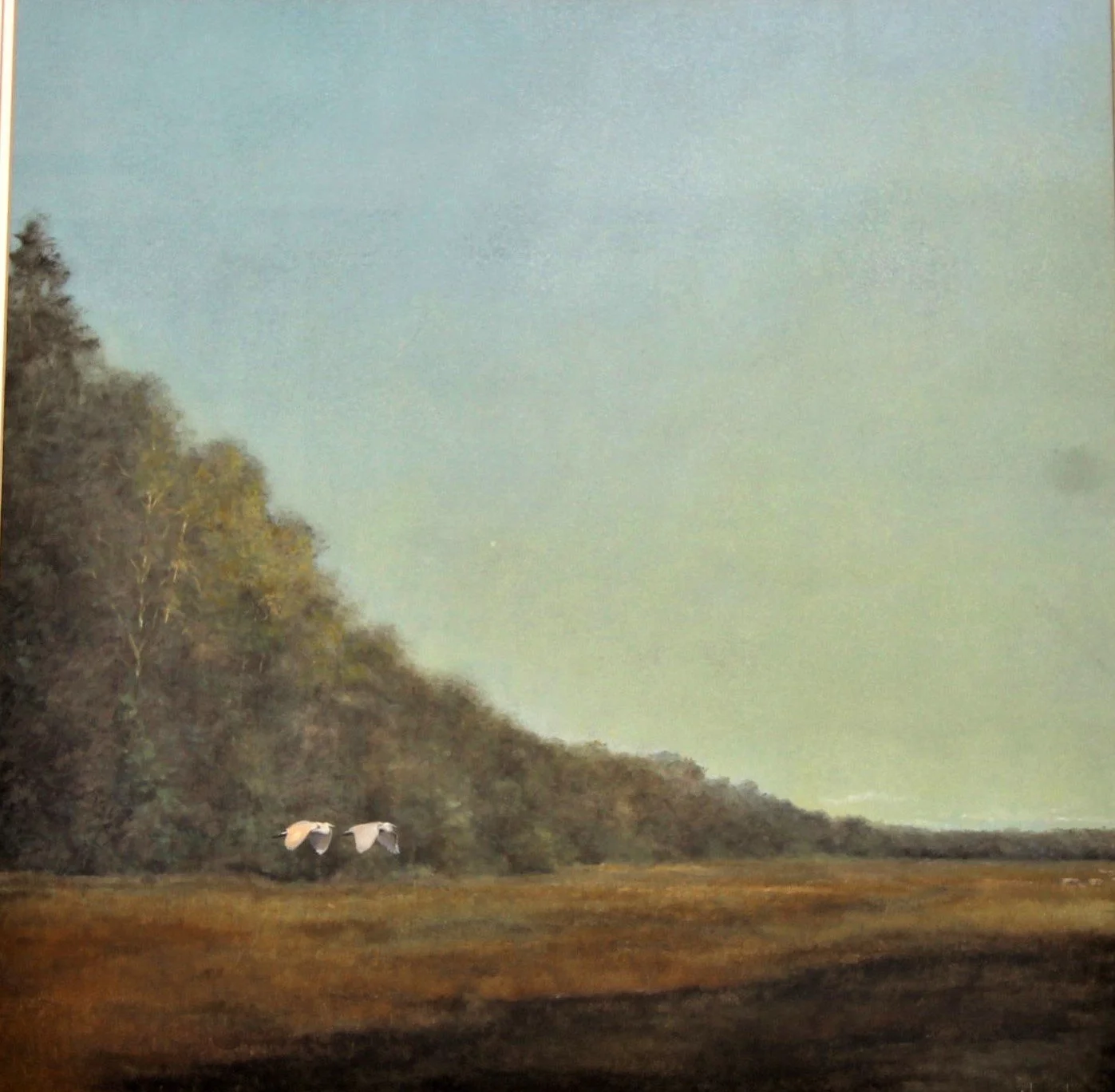 A landscape painting of a marshy area with two white birds flying near the ground, a treeline on the left, and a cloudy pale green sky.