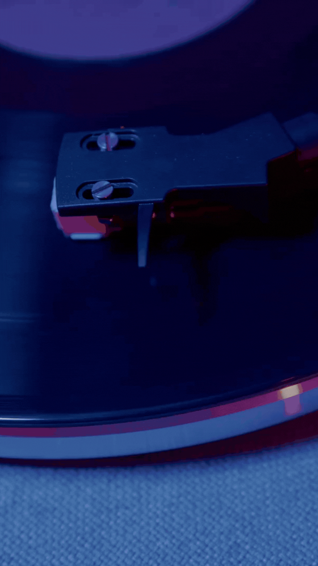 Close-up of a turntable's tonearm and stylus resting on a black vinyl record.