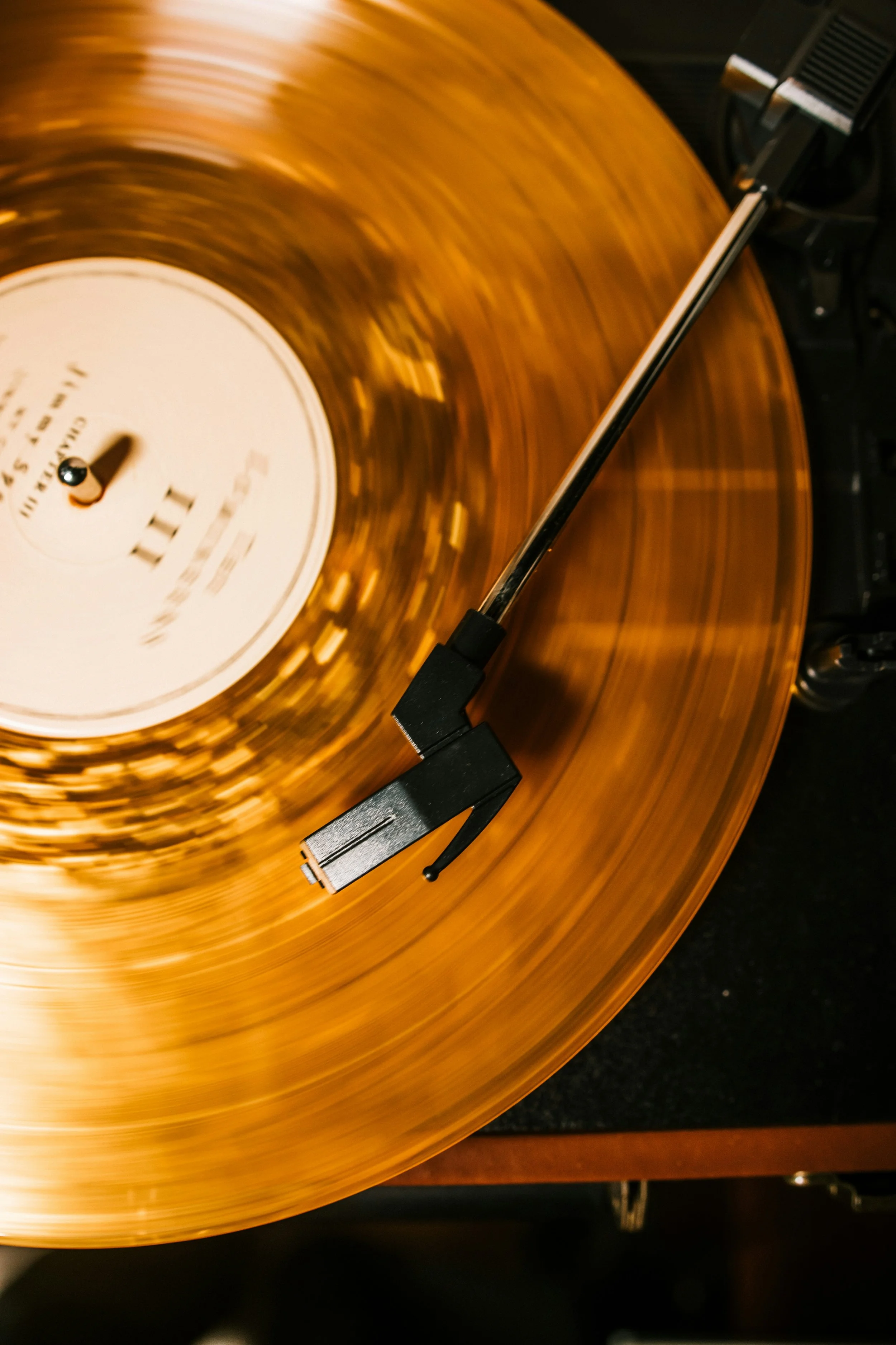 Close-up of a spinning vinyl record on a turntable, with the tonearm in motion.