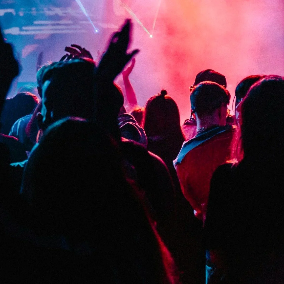 People dancing at a corporate event with colorful lighting and smoke effects.