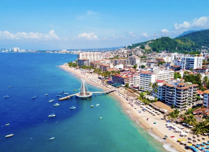 Aerial view of Puerto Vallarta beachfront with hotels, marina, and Sierra Madre mountains along Mexico’s Pacific coast.