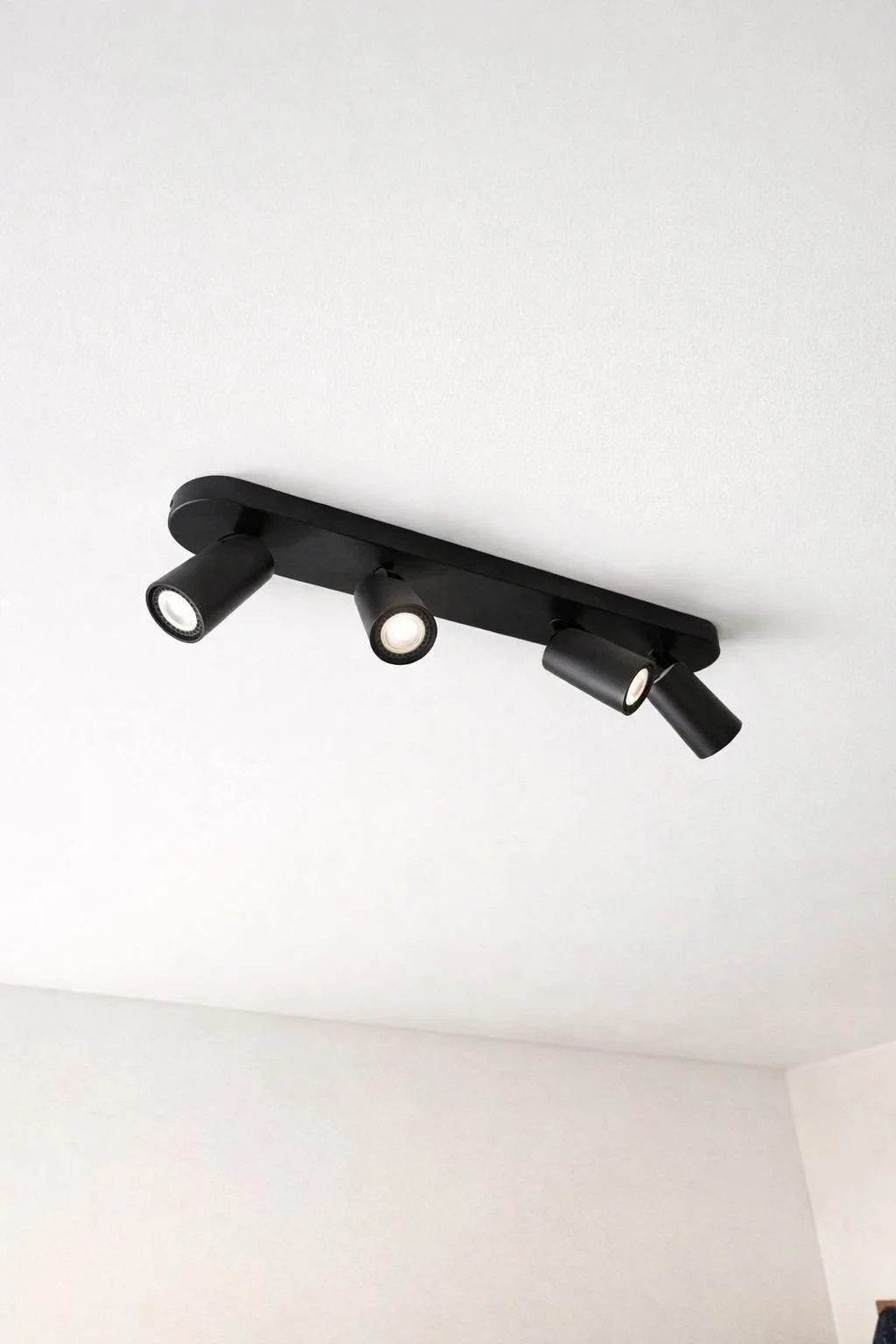 Een zwarte plafondspot bevestigd door een elektricien aan een witte plafondplaat in de regio Scherpenheuvel.