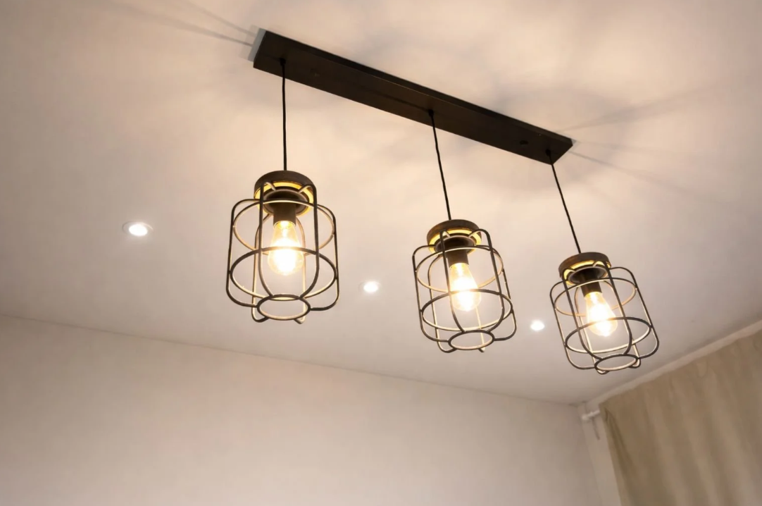 Ceiling light fixture with five exposed bulbs mounted on a brass base against a light blue ceiling.