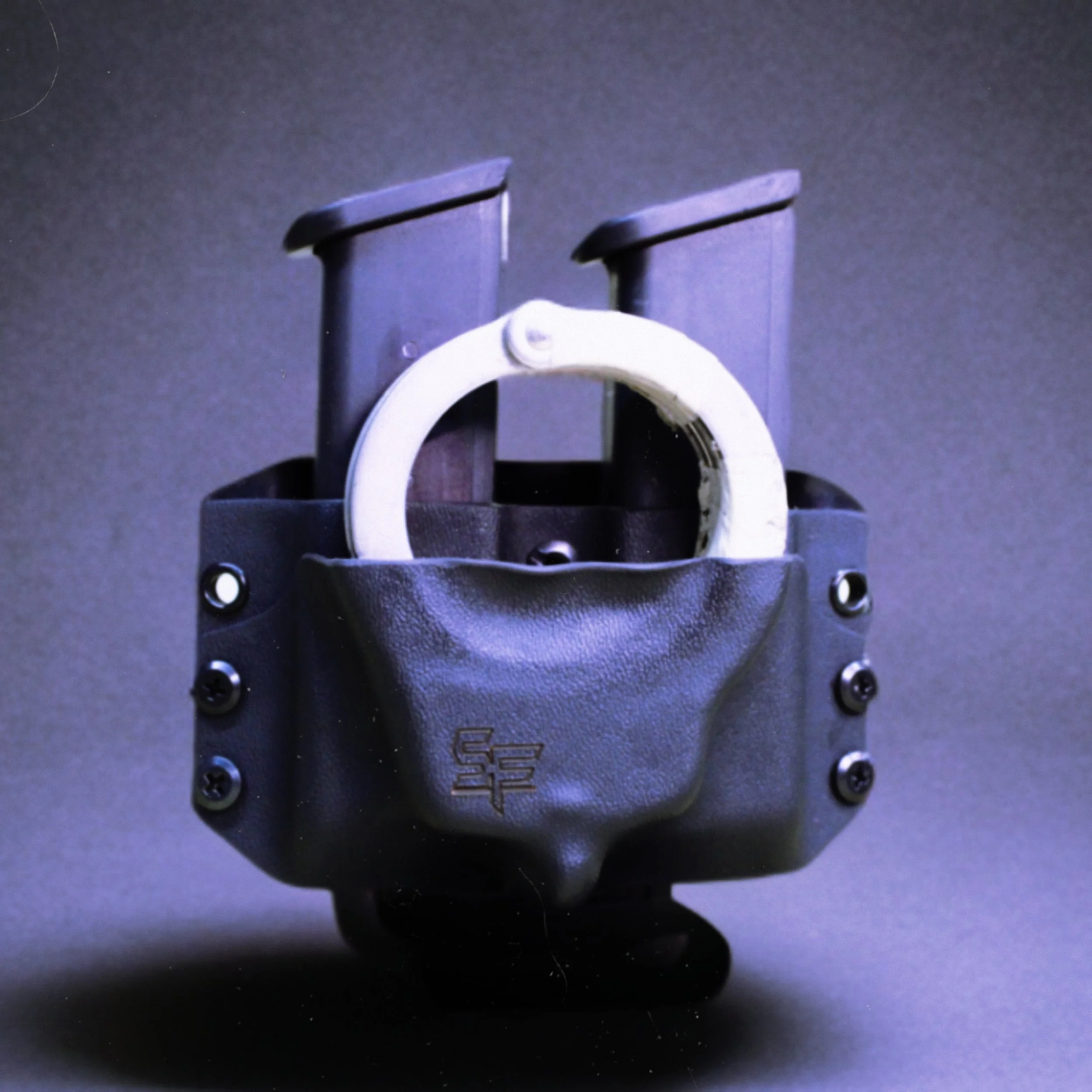 A police officer's holster with a white handcuff inside, placed against a dark background.