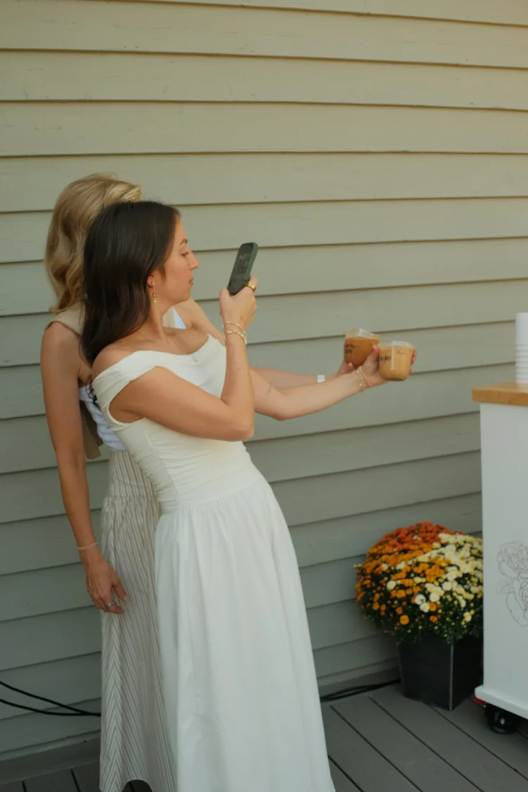 Two guests photographing their iced coffees at a shower