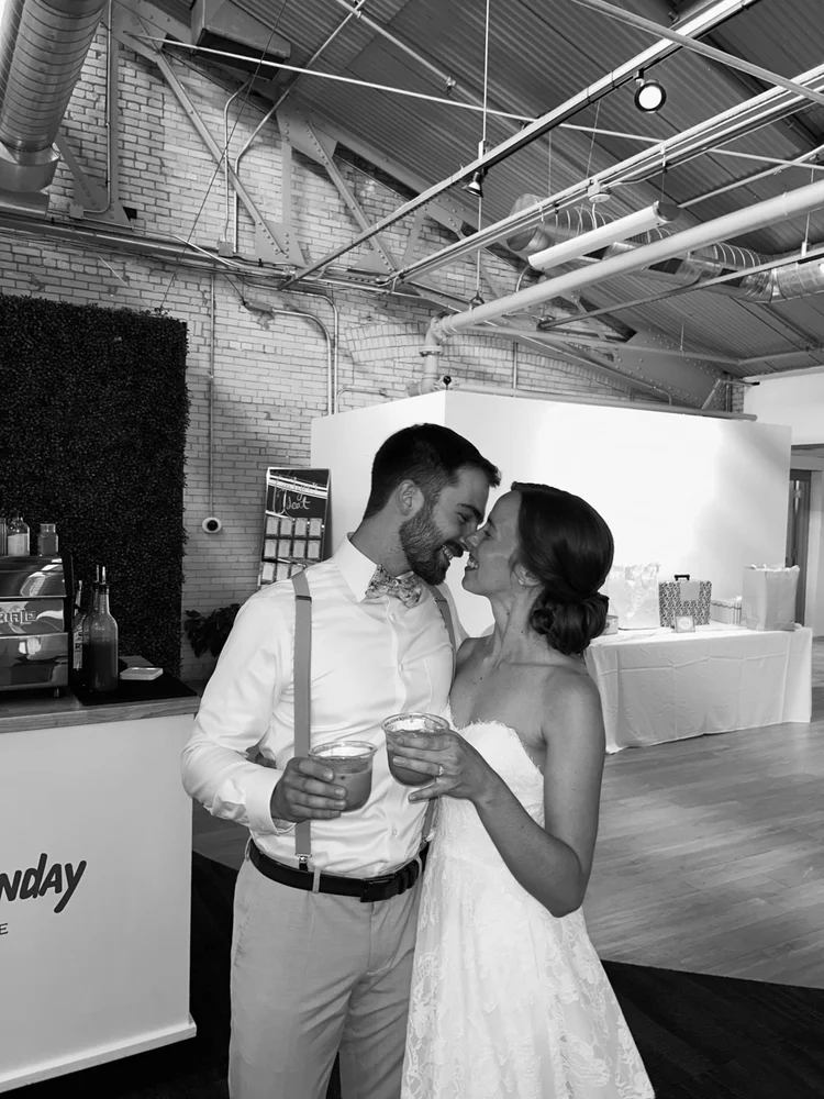 Bride and groom kissing while holding coffee cups at a wedding with the Slow Sunday cart