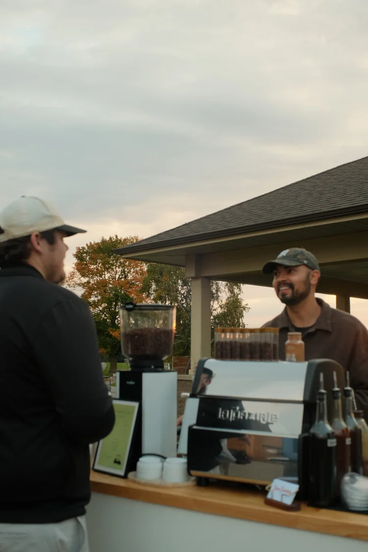 Barista handing a drink to a guest at the coffee cart under an outdoor pavilion