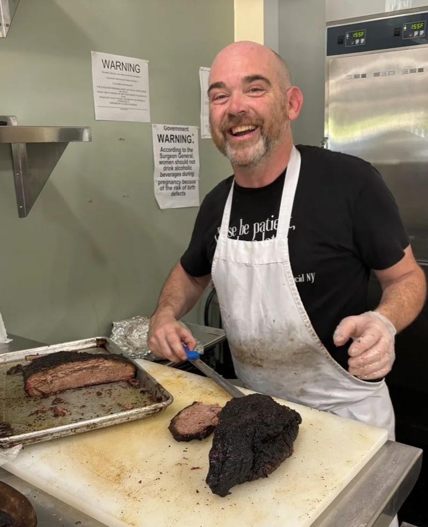 Jonathan Gravatt slicing birsket at West Shore BBQ, the best barbecue in Lake Placid.