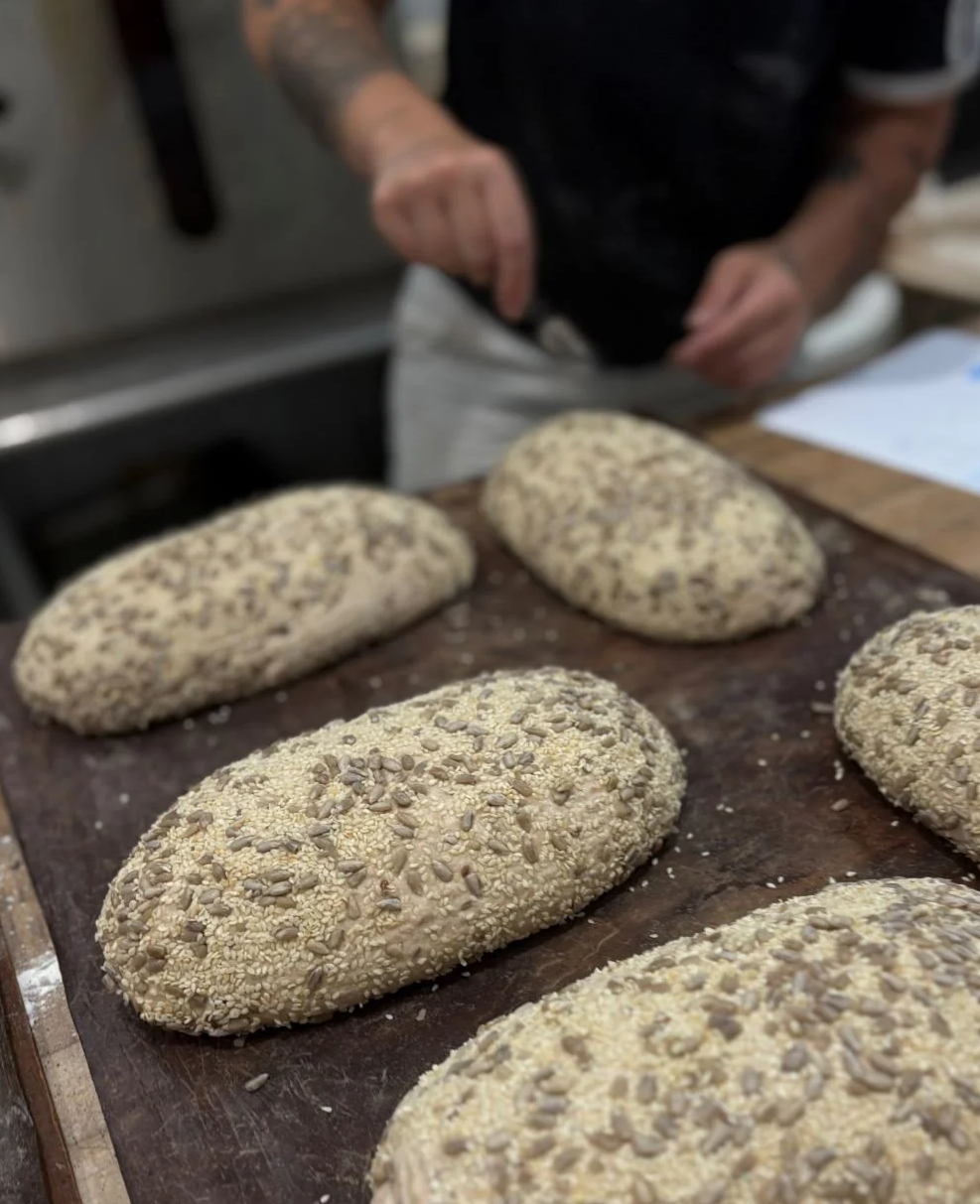 Seeded loaves of bread about to be scroed by Courtney Marvin of the Drifter's loaf.