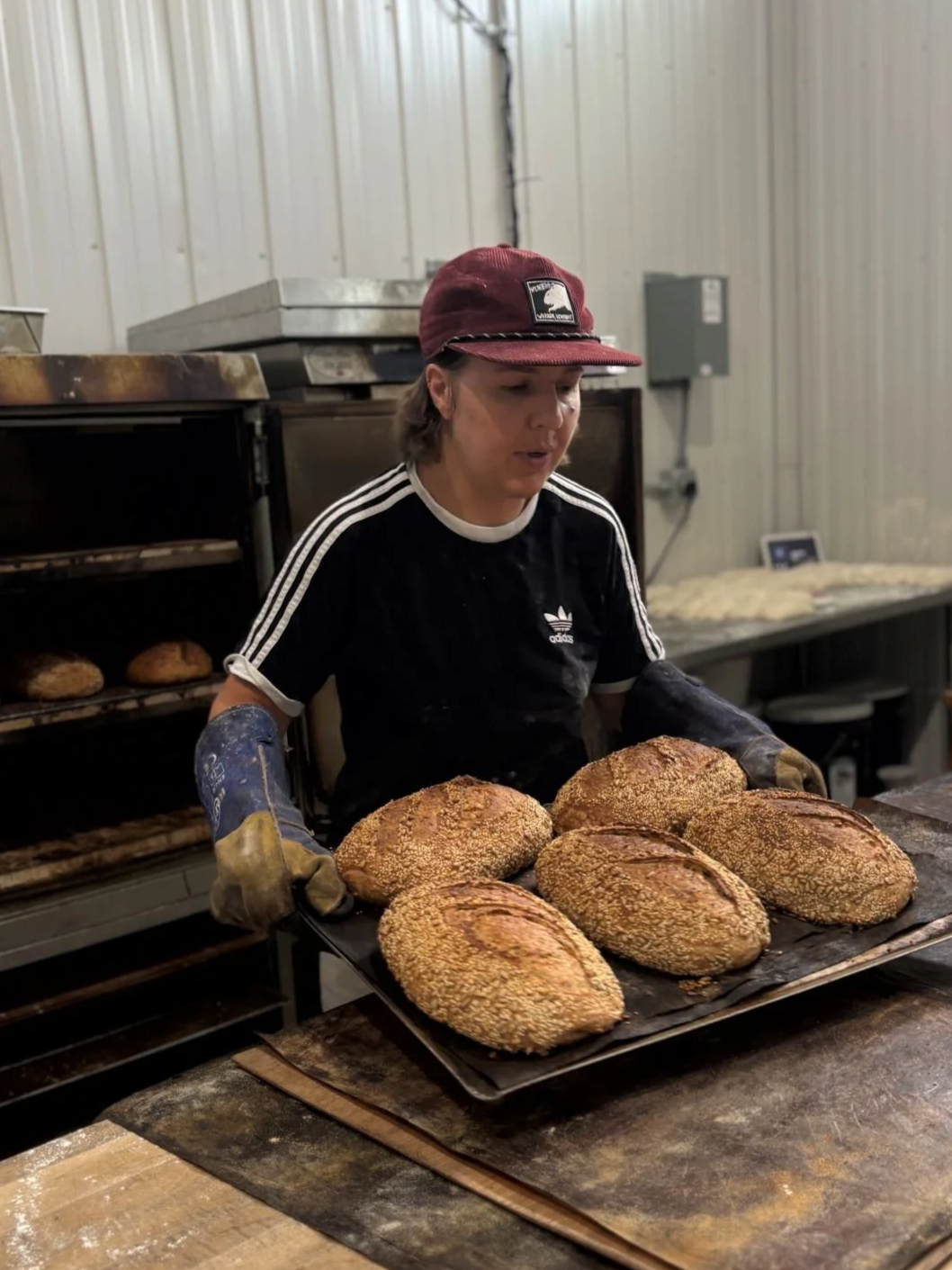 Courtney Marvin of The Drifter's Loaf in Elizabethtwon removing  bread from oven.