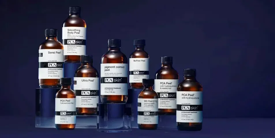 Collection of PCA Skin bottles with various skincare products on a dark background.