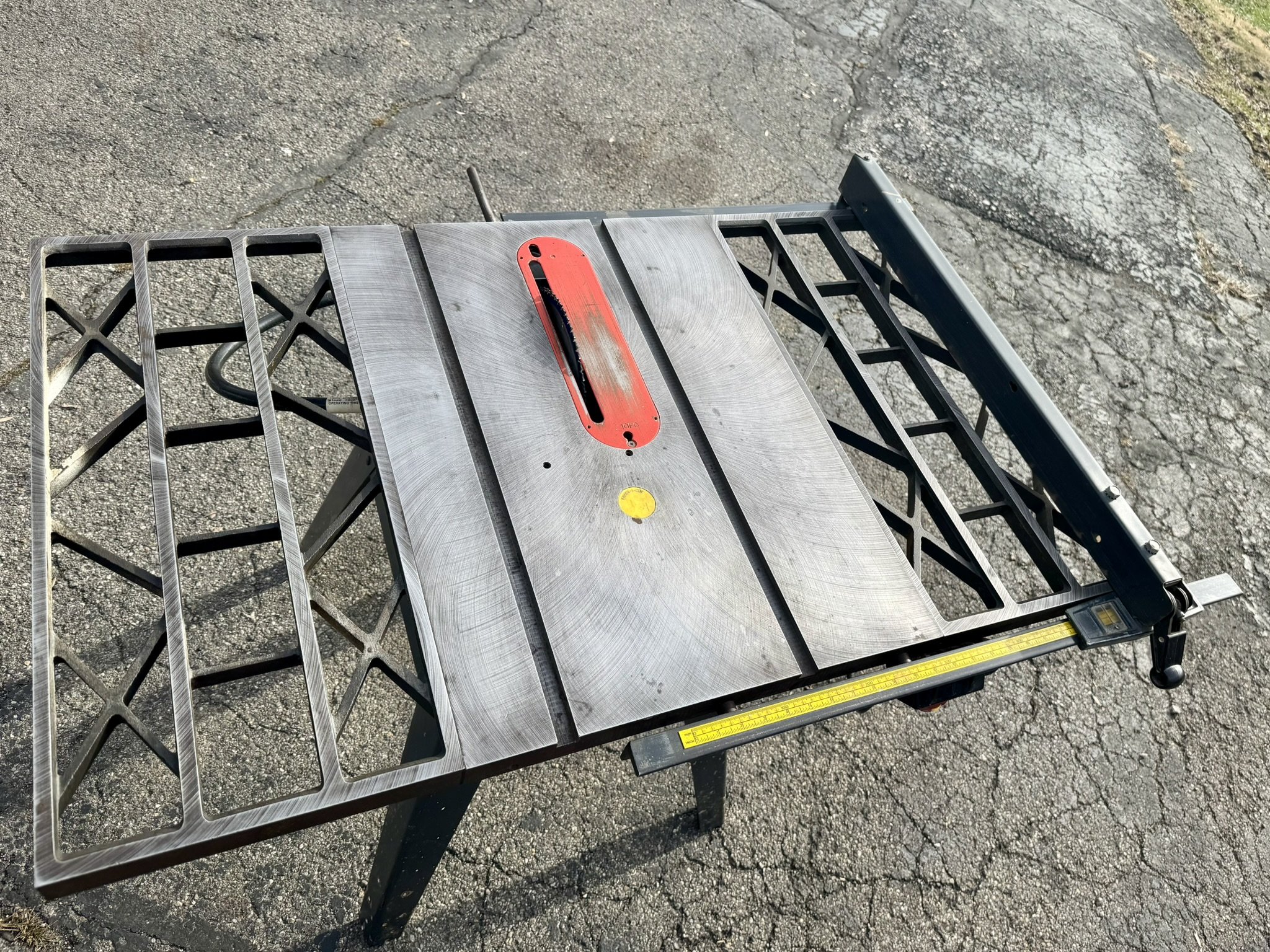 Close-up detail of a polished cast iron table saw top and webbed extension wings showing the precision miter gauge slots.