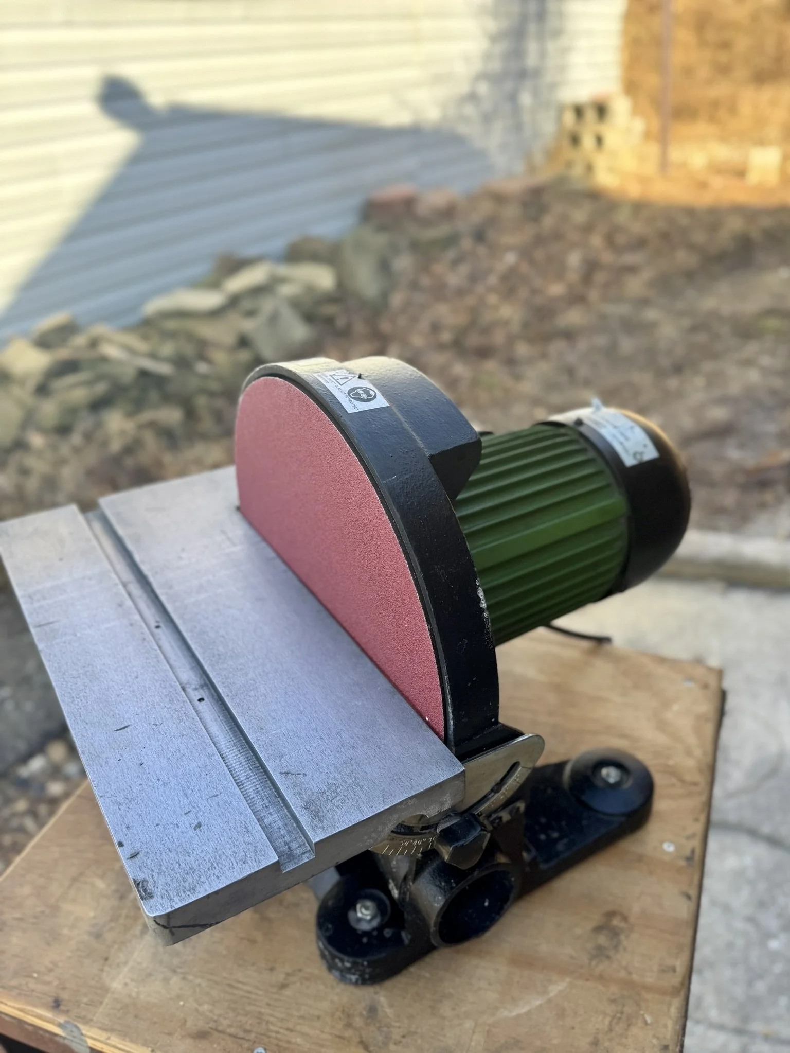 Central Machinery 12-inch disc sander with a green motor housing and cast iron base sitting on a workbench.