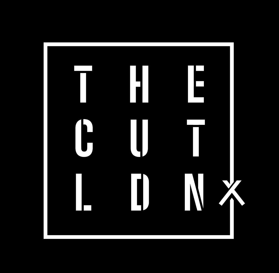 Black background with a white outlined square containing the words 'THE CUT' arranged in three rows and three columns, with an arrow pointing downward from the top right corner.