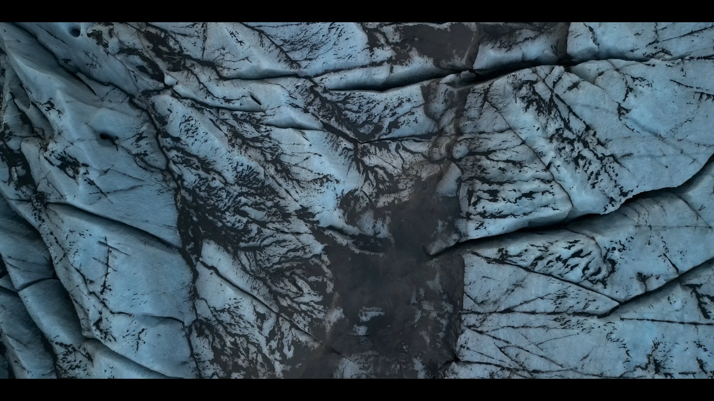 Close-up of a glacier with black streaks and cracks in the ice.