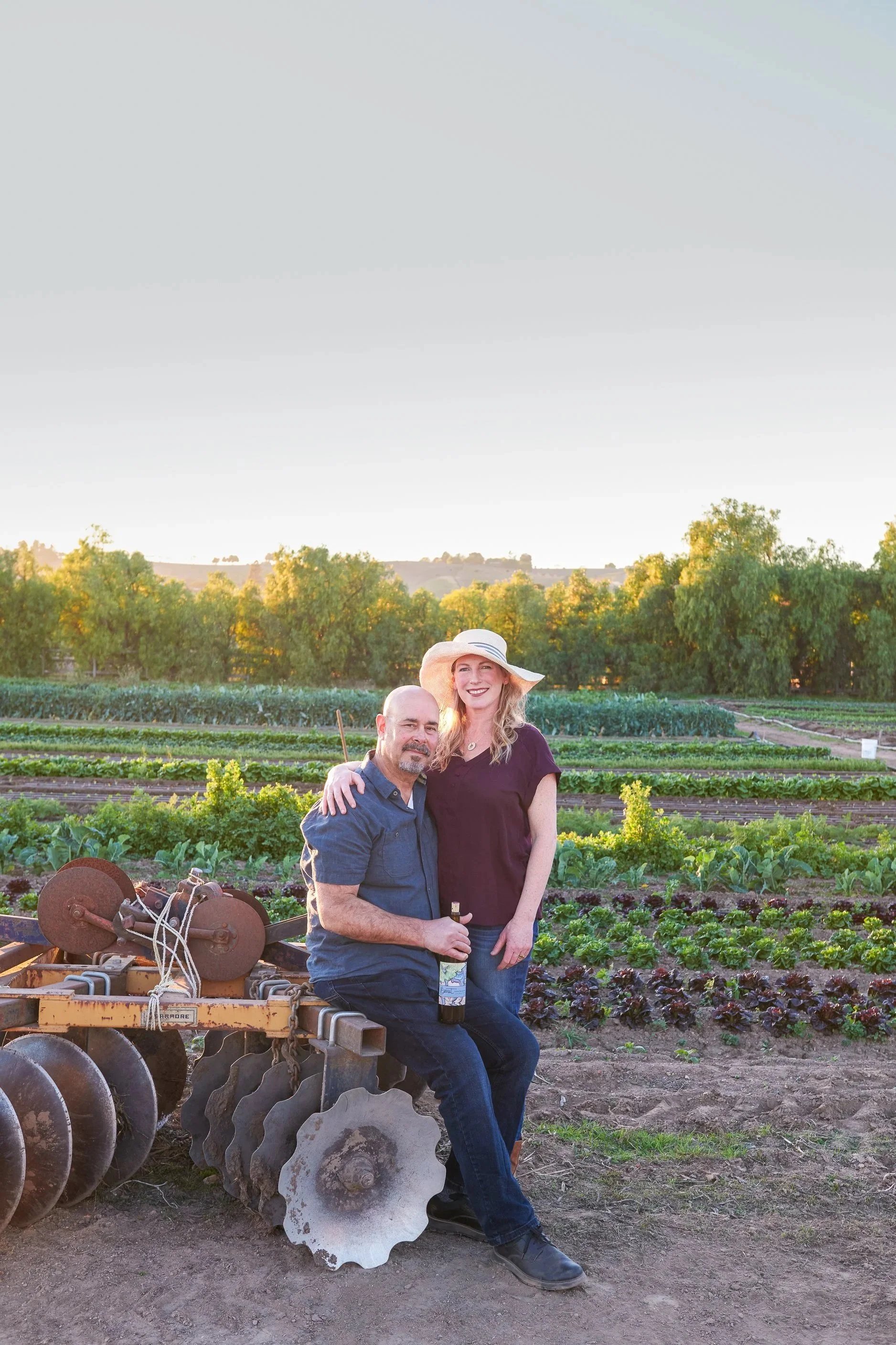 Sam and Shawnda on their Cafe Farm with lettuce and tractor in the background