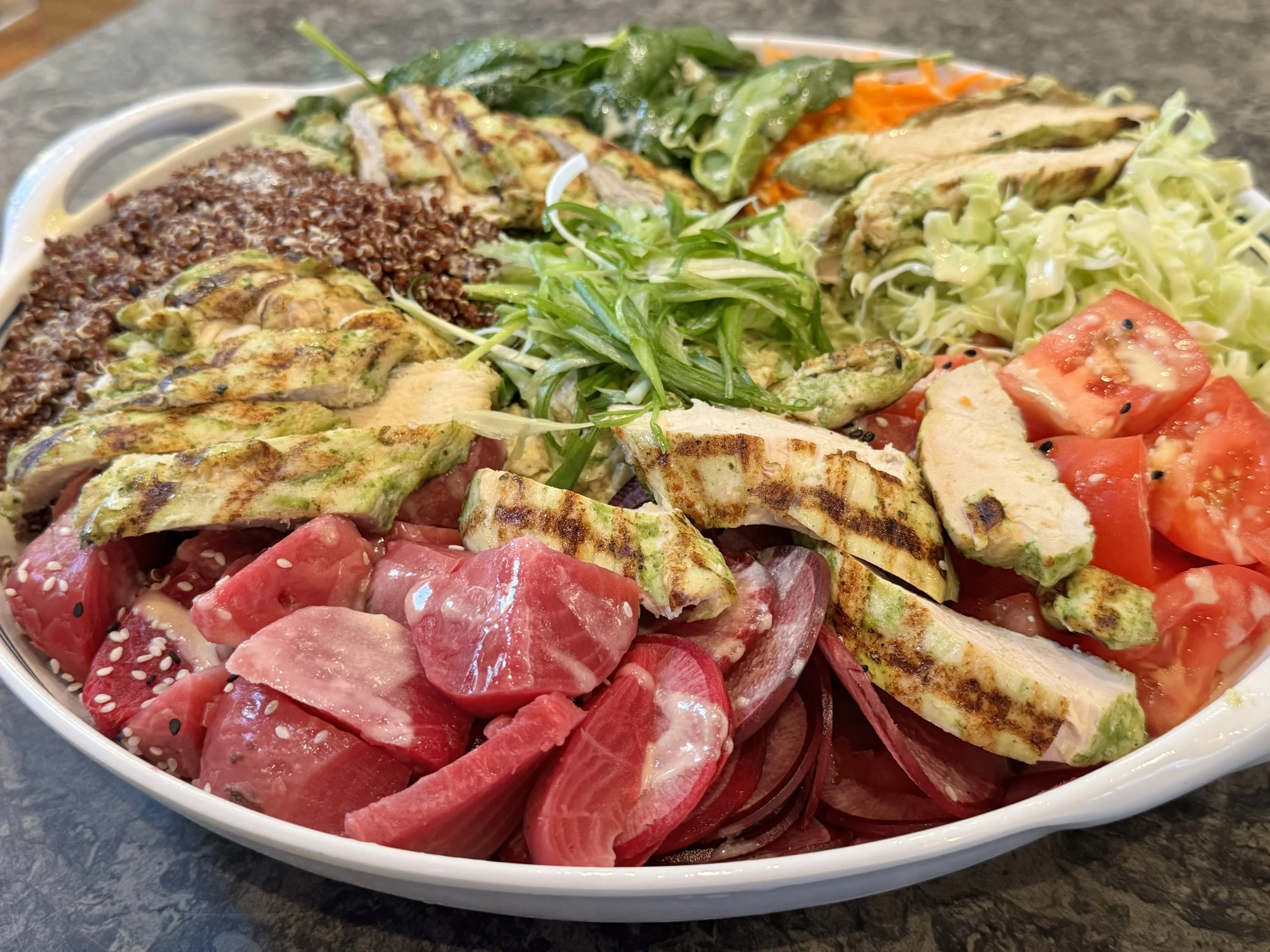Image of a colorful platter with beets, chicken quinoa, tomatoes cabbage and other greens