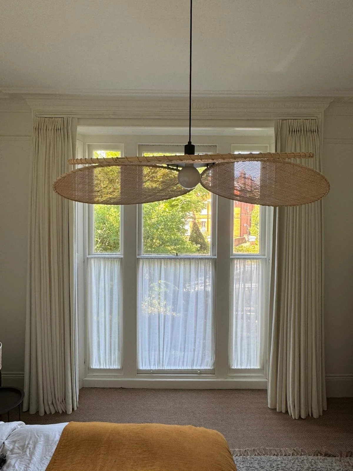 View of a room with large windowed doors, beige curtains, and a modern hanging light fixture.
