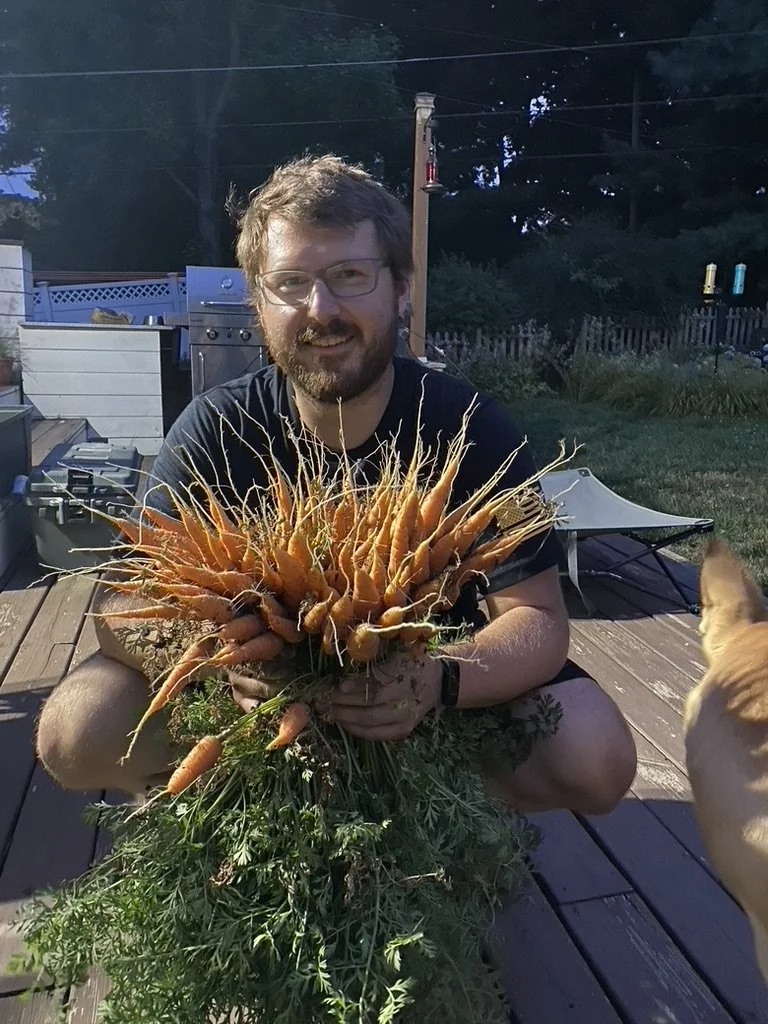 Man (John) holds a huge handful of freshly picked carrots