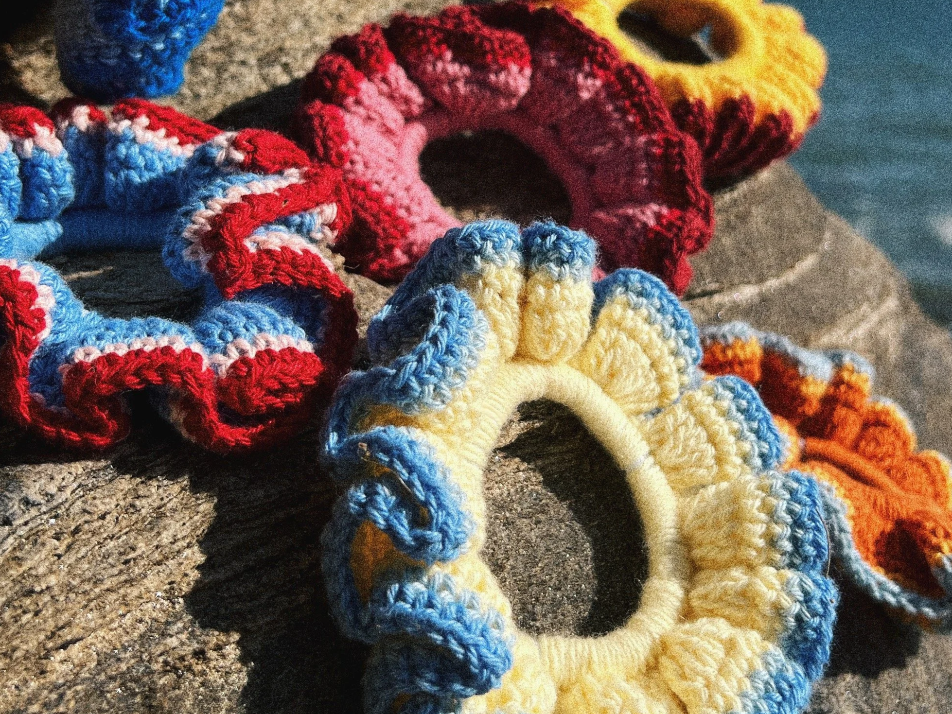 Un ensemble d’élastiques en crochet multicolores, disposés sur une surface rugueuse en pierre.