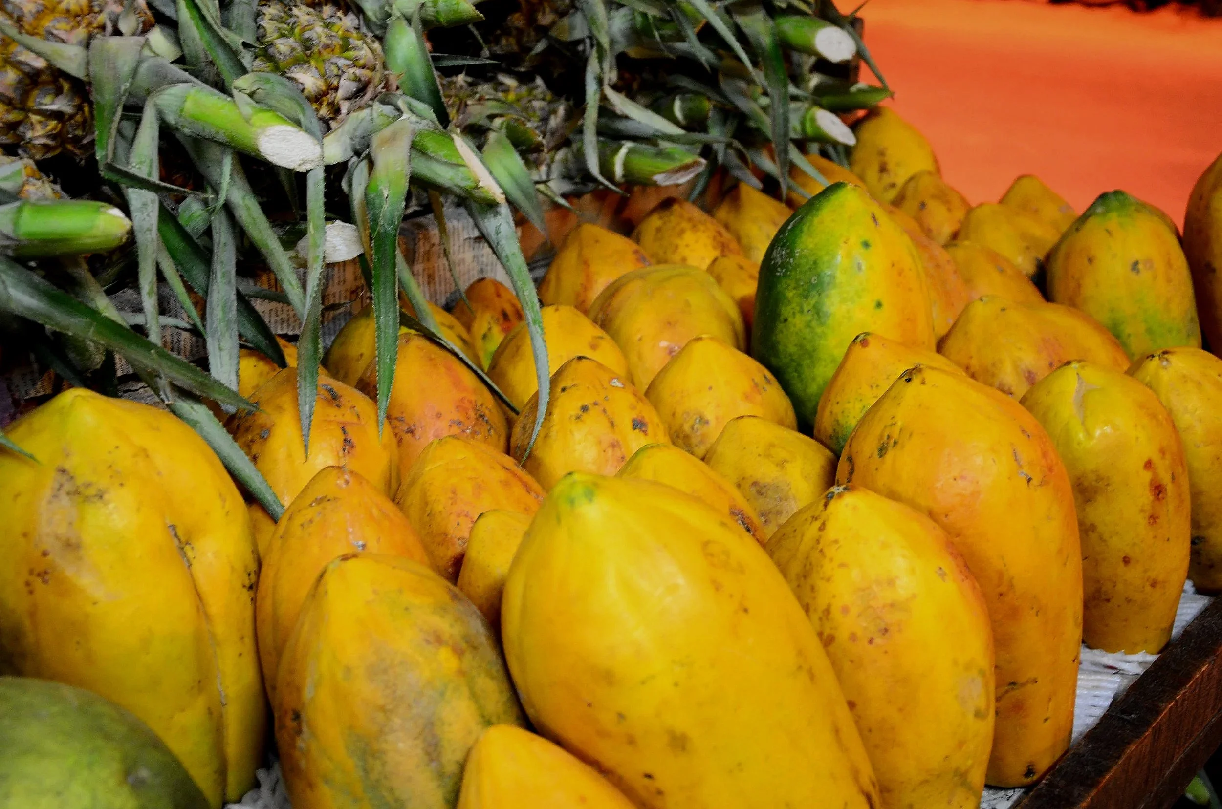 Ananas et papayes jaunes disposés en tas.