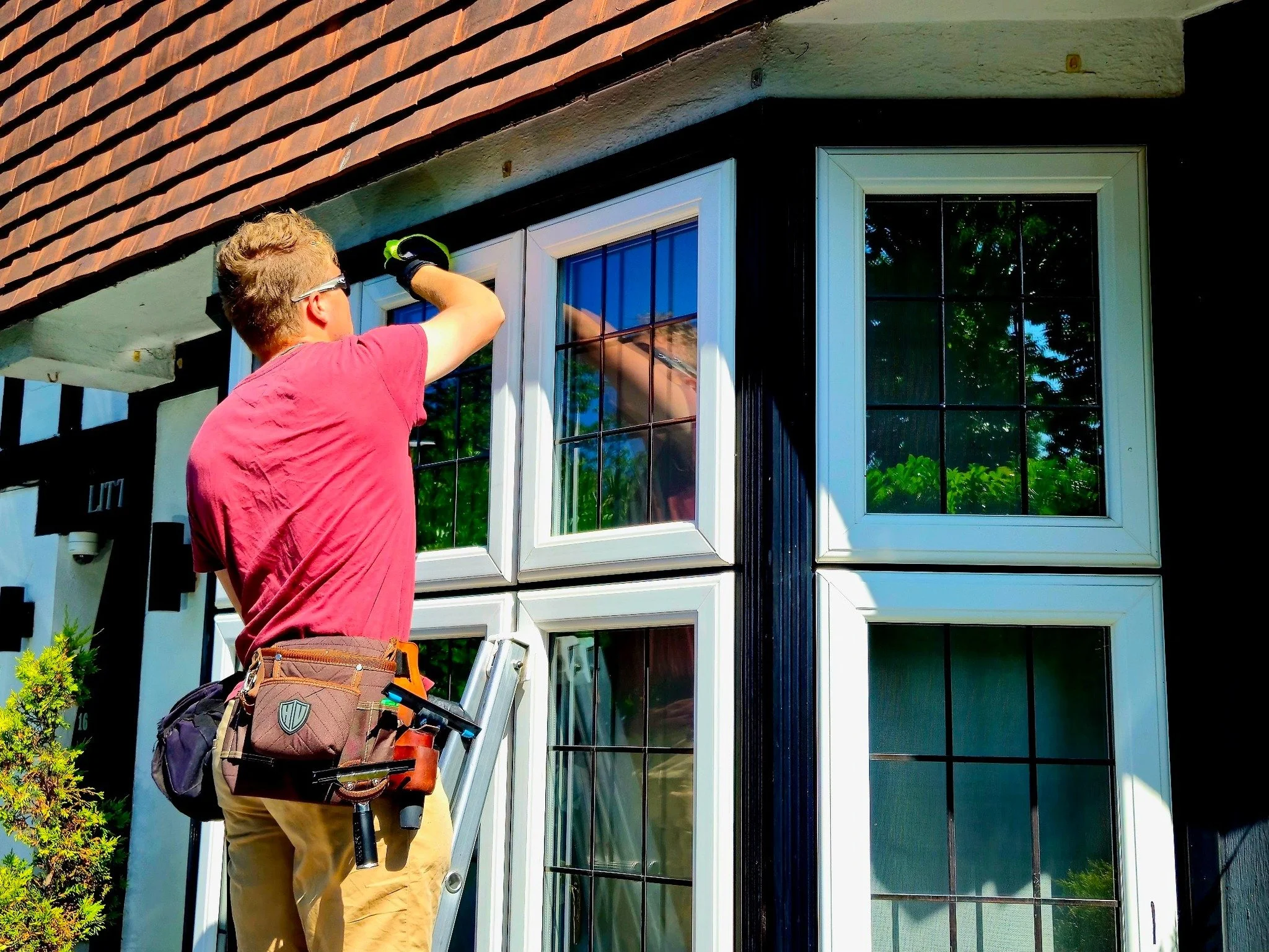 A man standing on a ladder cleaning the window of a house.