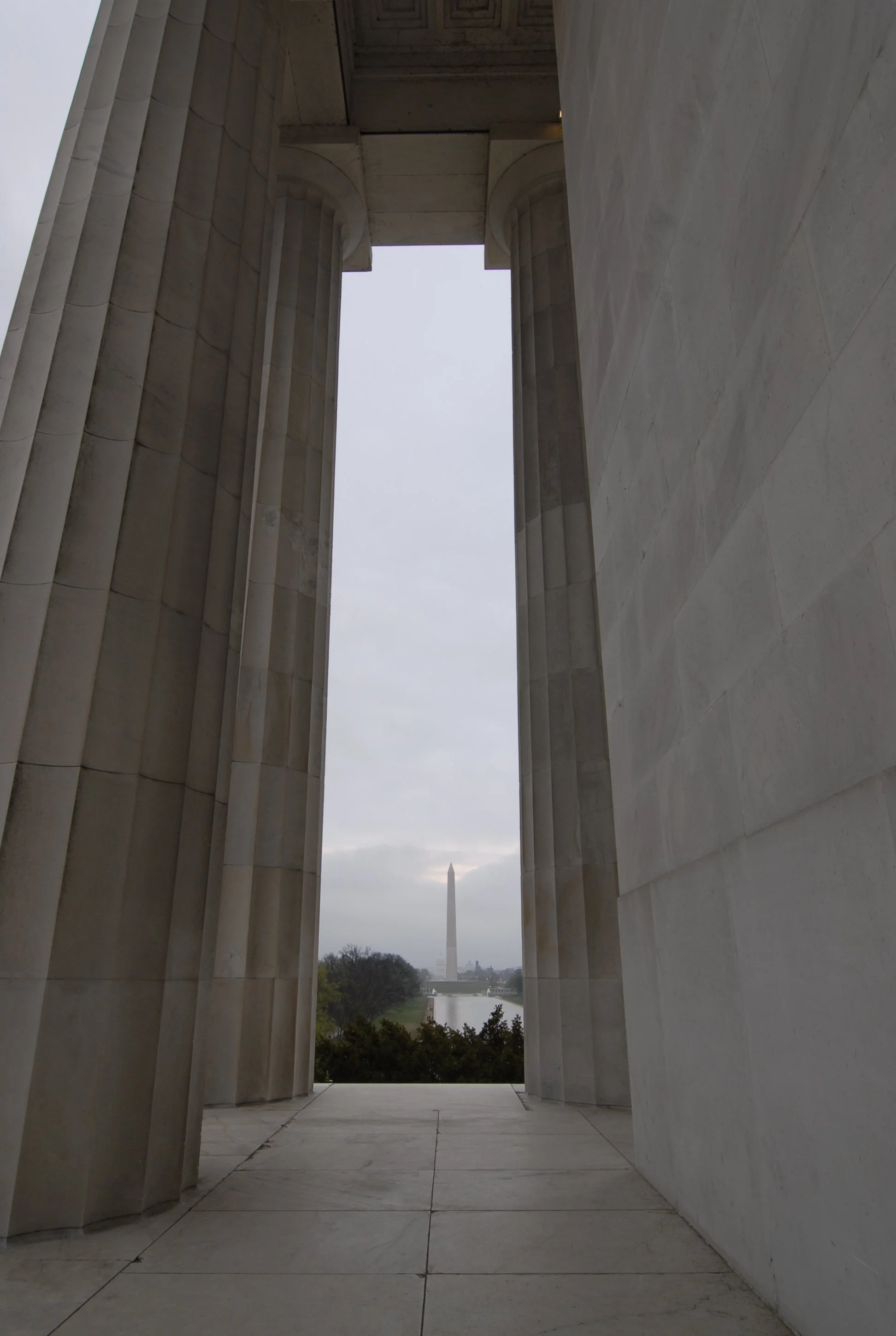 View through the columns of the Lincoln Memorial towards the Washington Monument and the landscape beyond on a cloudy day
