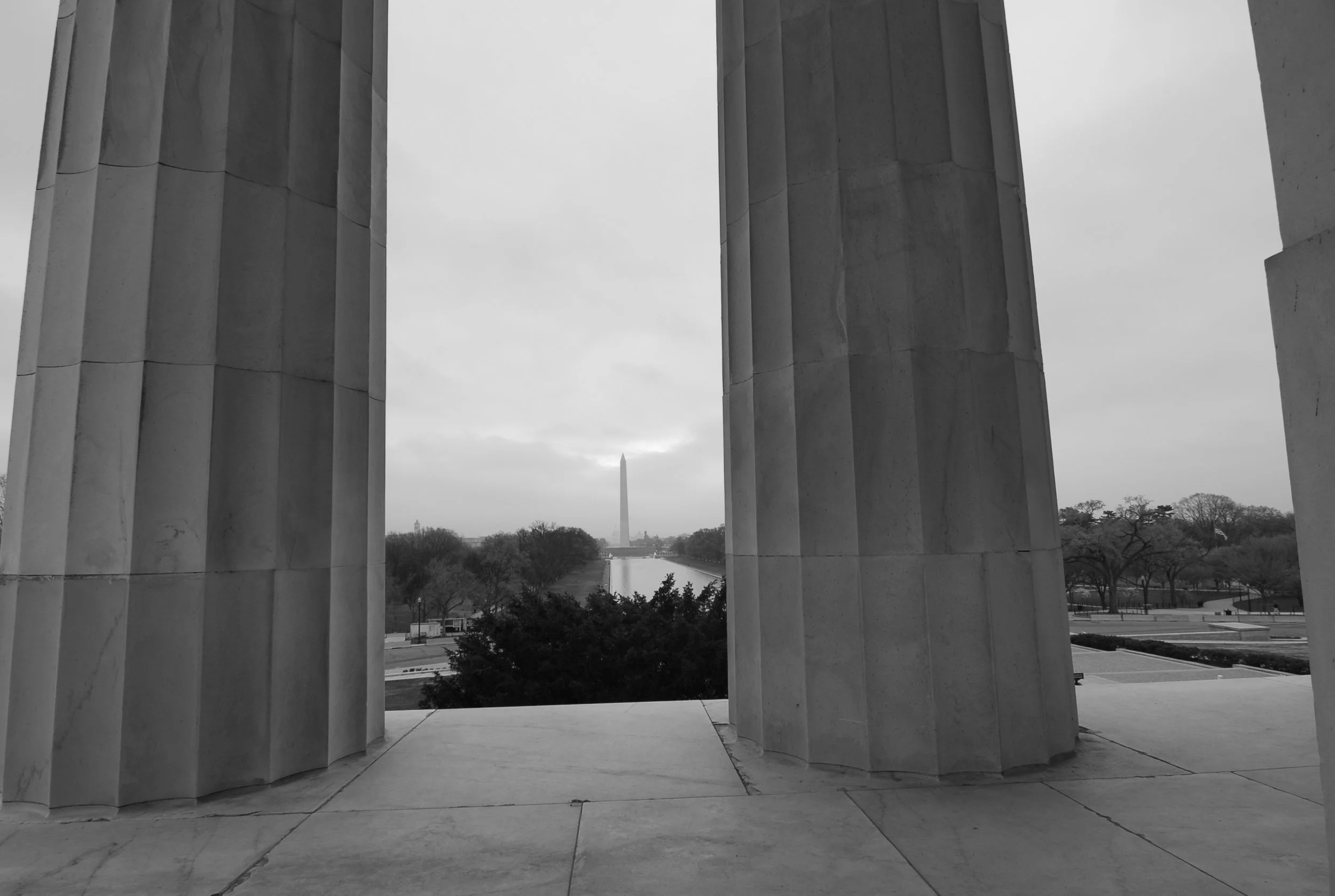 View of the Washington Monument through the columns of the Lincoln Memorial, black and white photograph