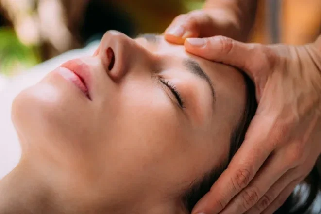 A woman receiving a massage, lying down with her eyes closed.