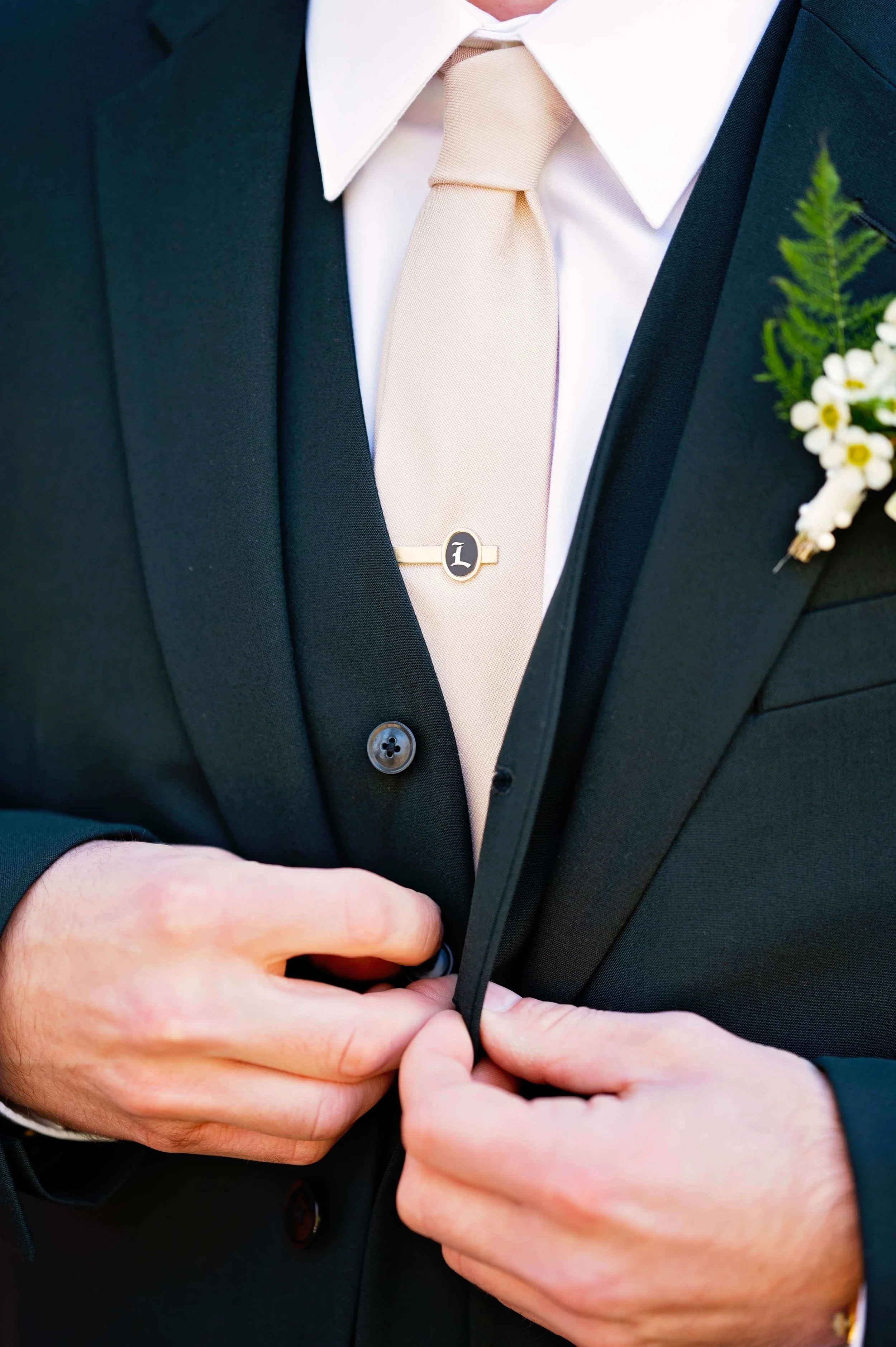 White wildflower and fern boutonniere on a dark suit with champagne tie, classic groom detail, New England wedding by Milkweed Floral Co