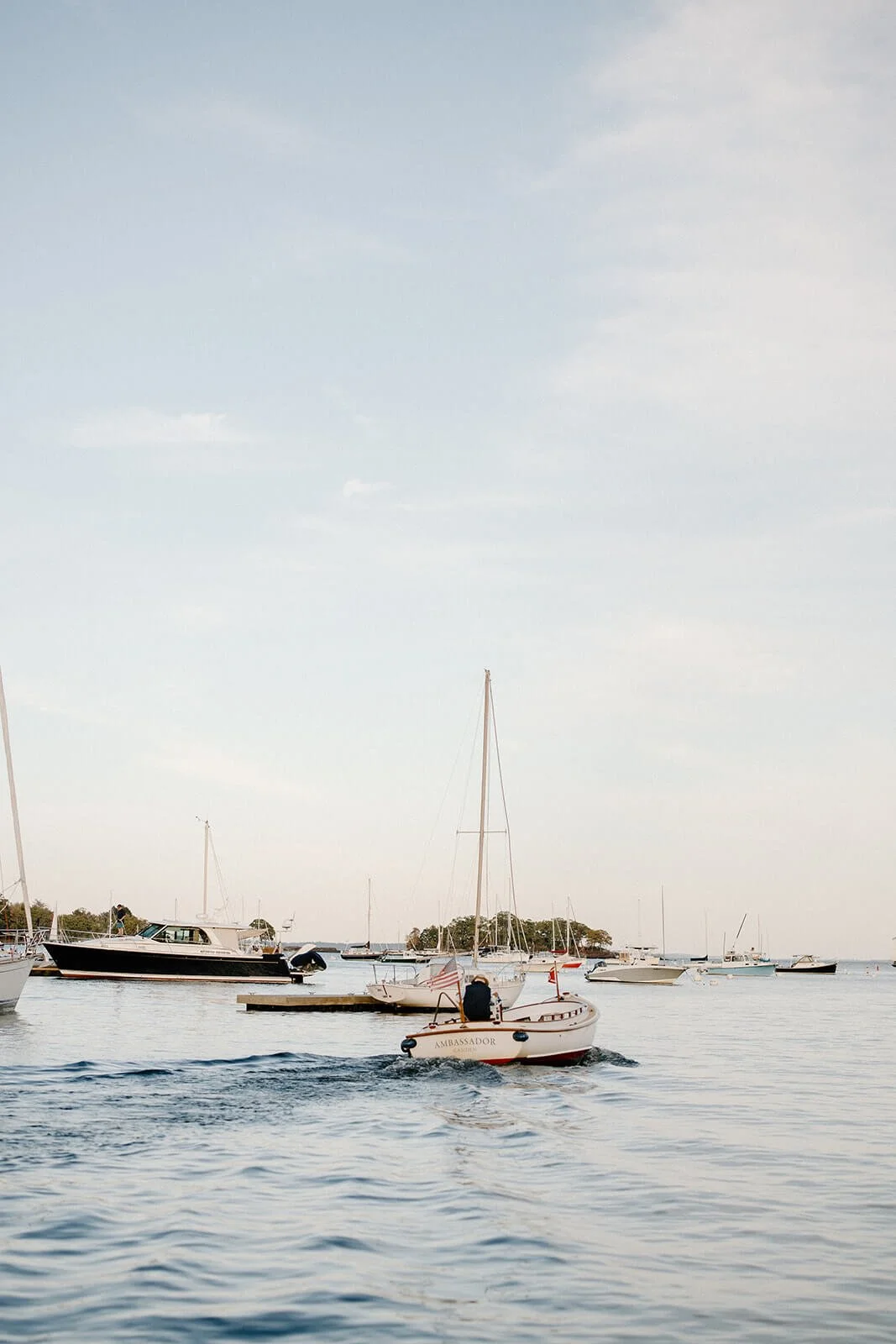 Sailboats and motorboats on a calm coastal Maine harbor at golden hour, wedding venue backdrop for a Milkweed Floral Co coastal wedding
