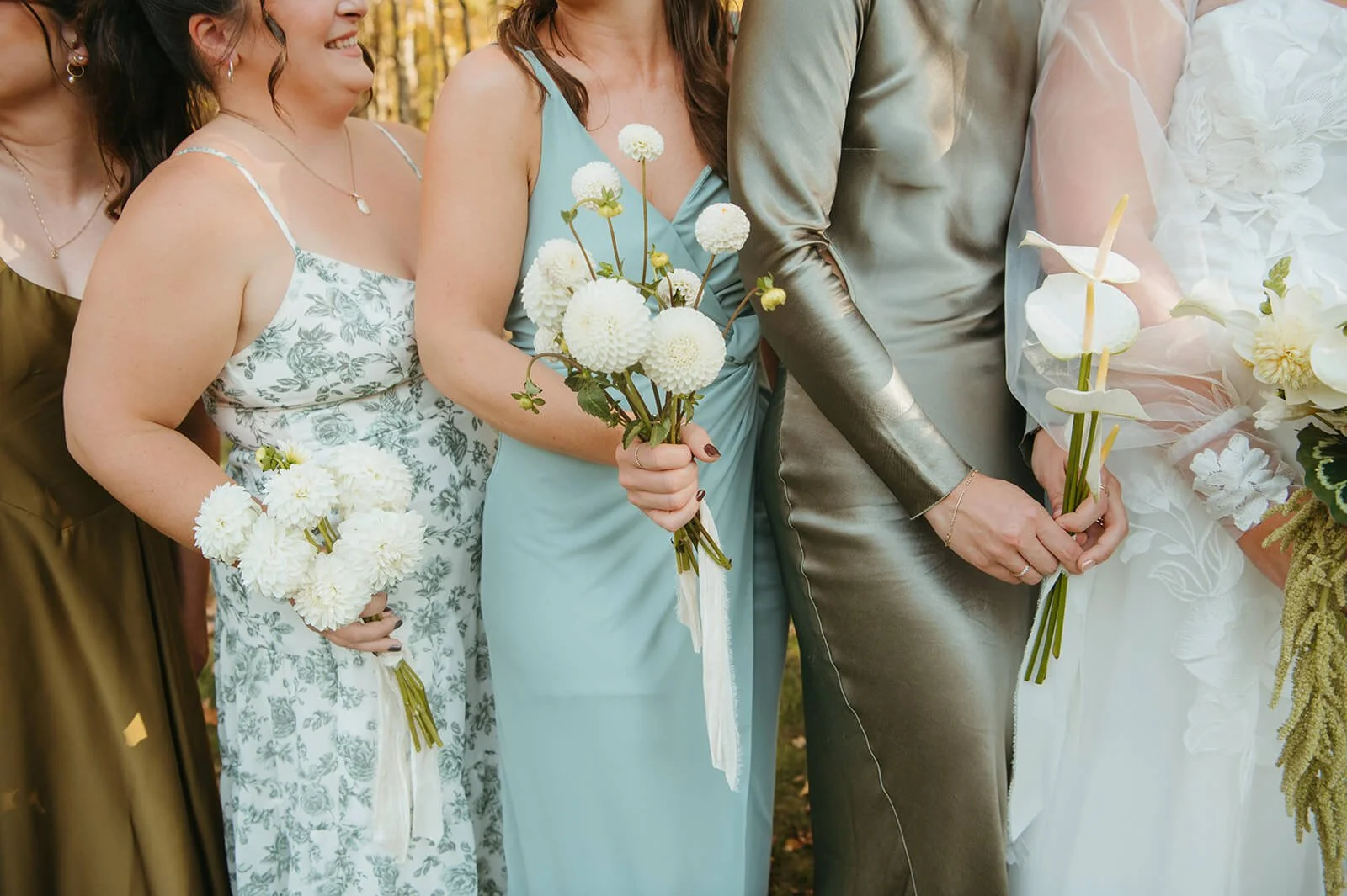 Bridesmaids in mismatched sage, blue, and olive dresses holding white dahlia and calla lily bouquets with ribbon streamers, New England fall wedding by Milkweed Floral Co