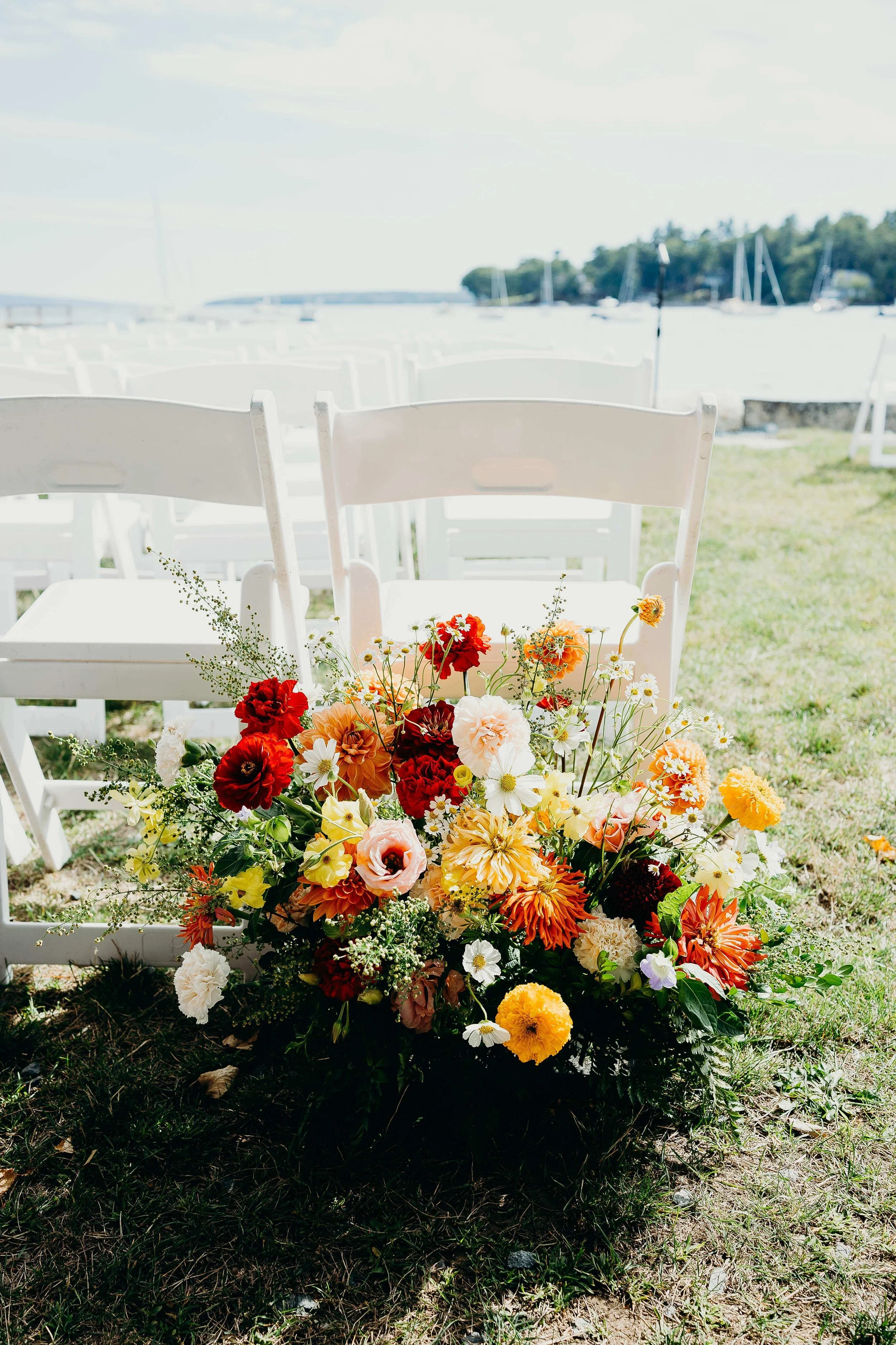 Wild garden ceremony aisle arrangement with dahlias, zinnias, and cosmos at a coastal New England wedding, Milkweed Floral Co