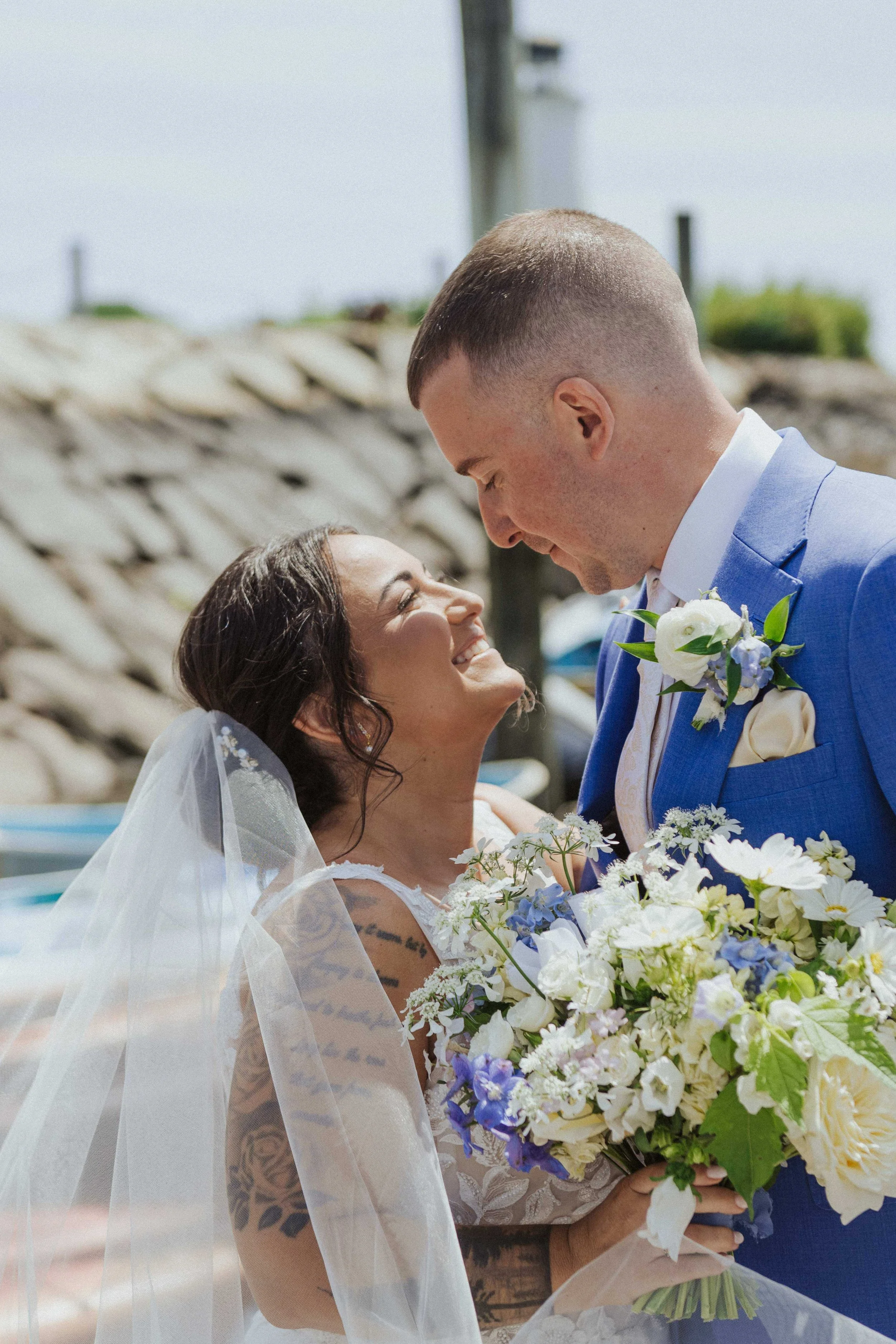 Bride and groom in Kennebunkport, Maine, with a coastal blue and white bouquet of delphinium and garden roses, Milkweed Floral Co