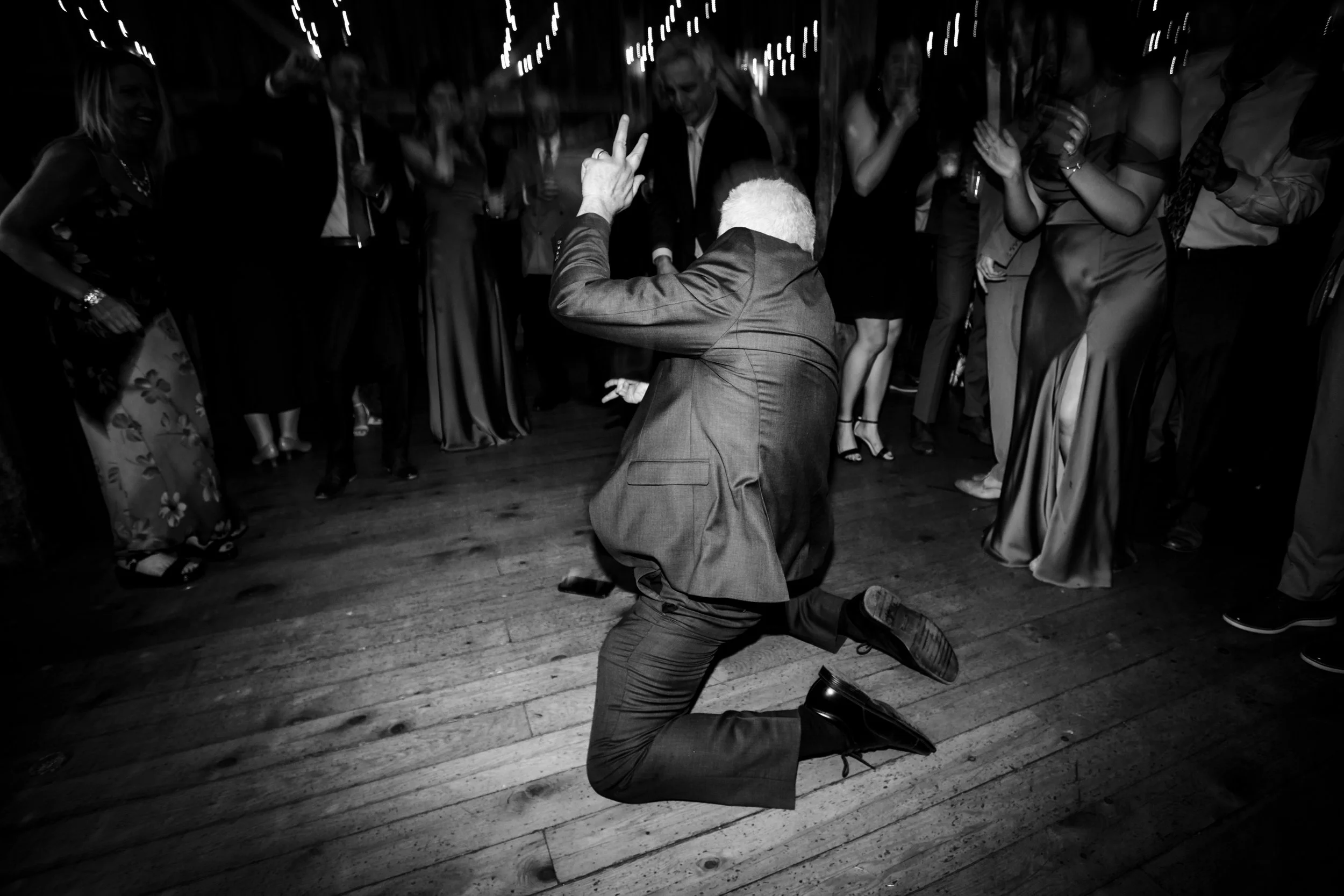 Man in suit on dance floor, man is on his knees with hand in the air,fall wedding, The Barn at Walnut Hill Maine, wedding florals by Milkweed Floral Co
