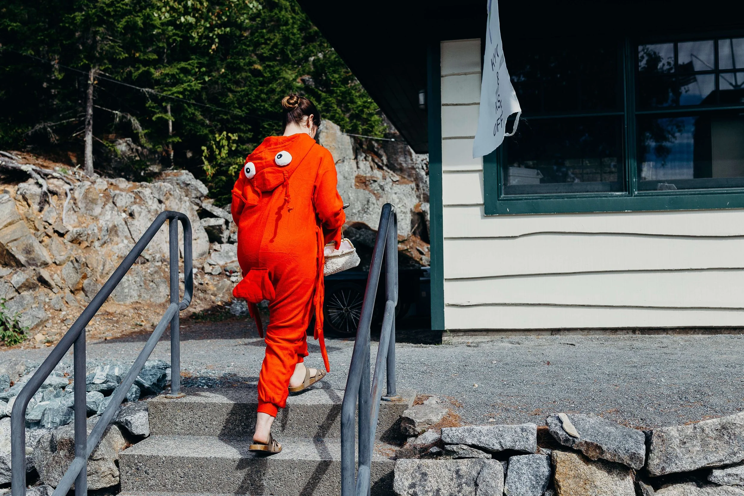 Woman in a lobster costume climbing the steps of Kollegewidgwok Yacht Club, Blue Hill Maine wedding by Milkweed Floral Co
