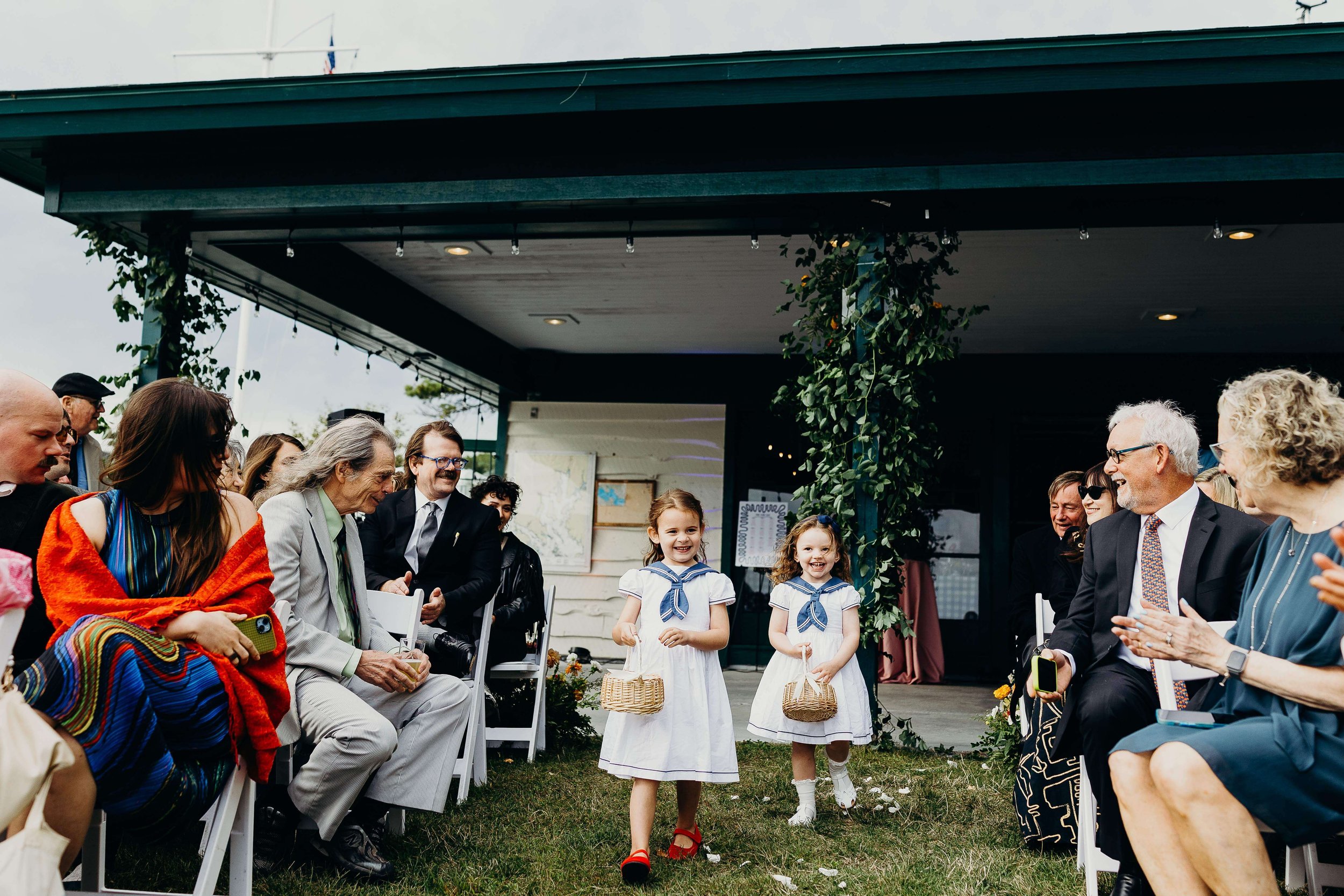 Flower girls in matching sailor dresses walking down the aisle during wedding processional, wedding florals by Milkweed Floral Co