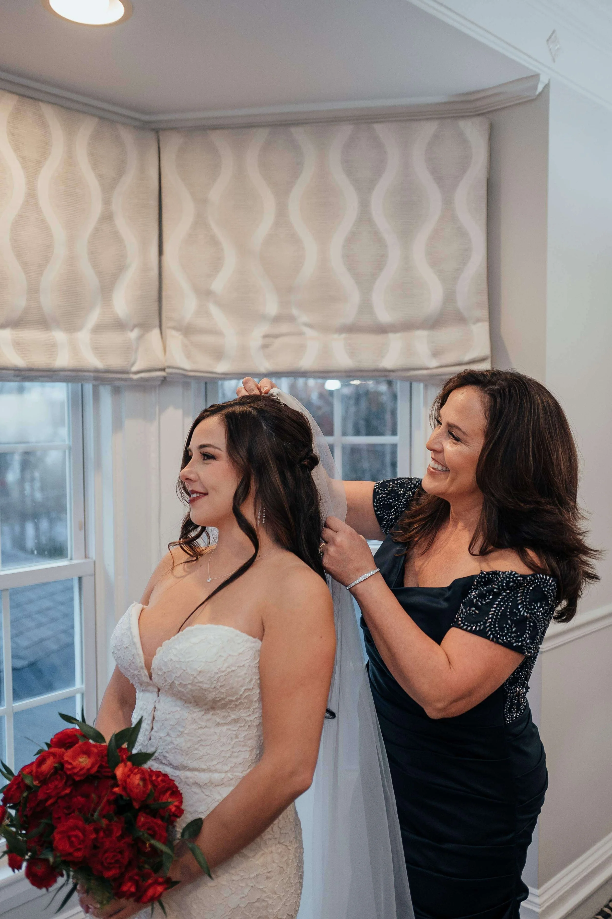Mother of the bride placing the veil while bride holds a lush red peony and rose bouquet, getting ready detail for a New England winter wedding by Milkweed Floral Co