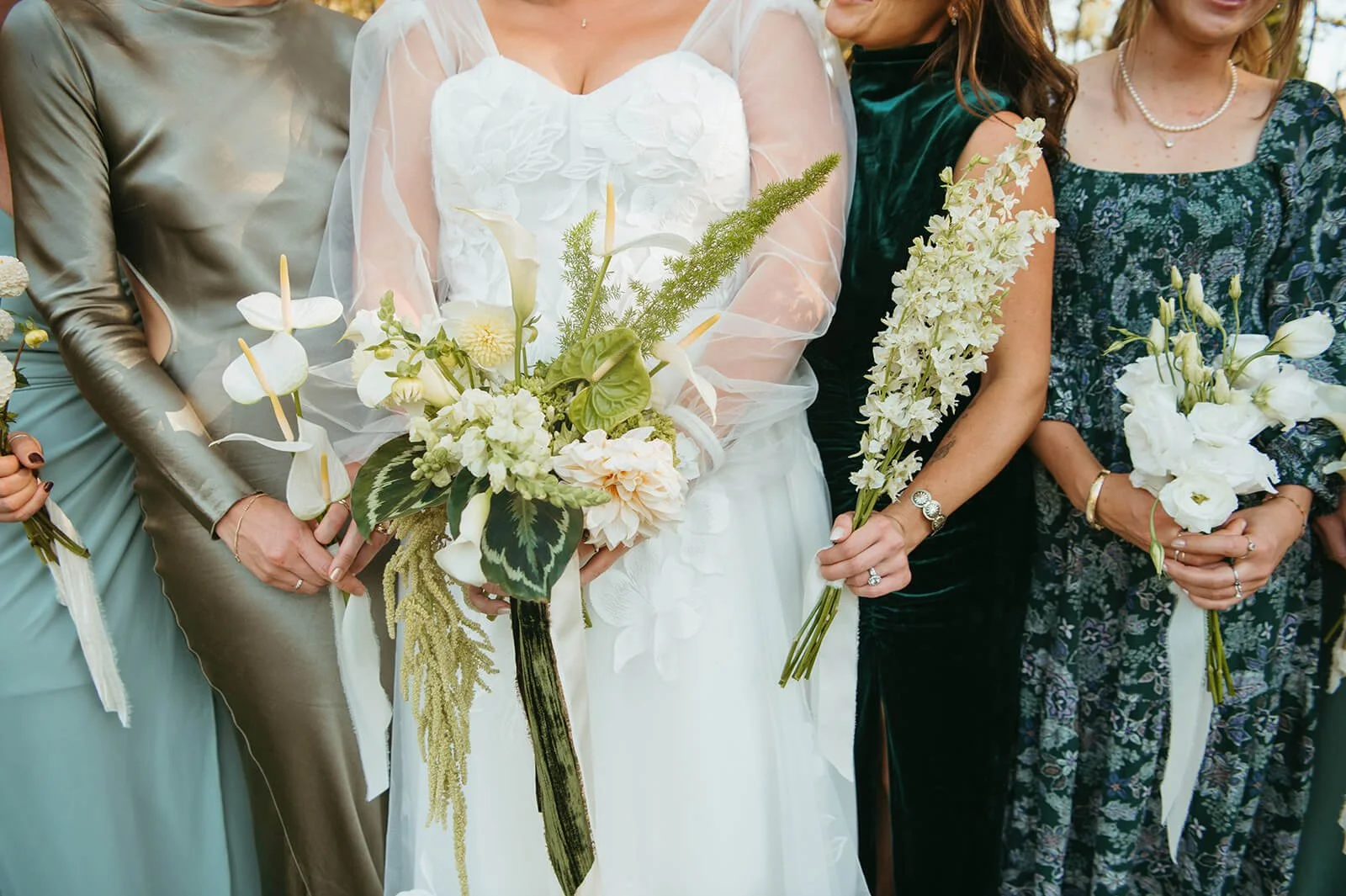 Bride holding a cascading bouquet of white anthurium, calla lilies, dahlias, and trailing amaranthus alongside bridesmaids in mismatched green dresses, Monson Massachusetts fall wedding by Milkweed Floral Co
