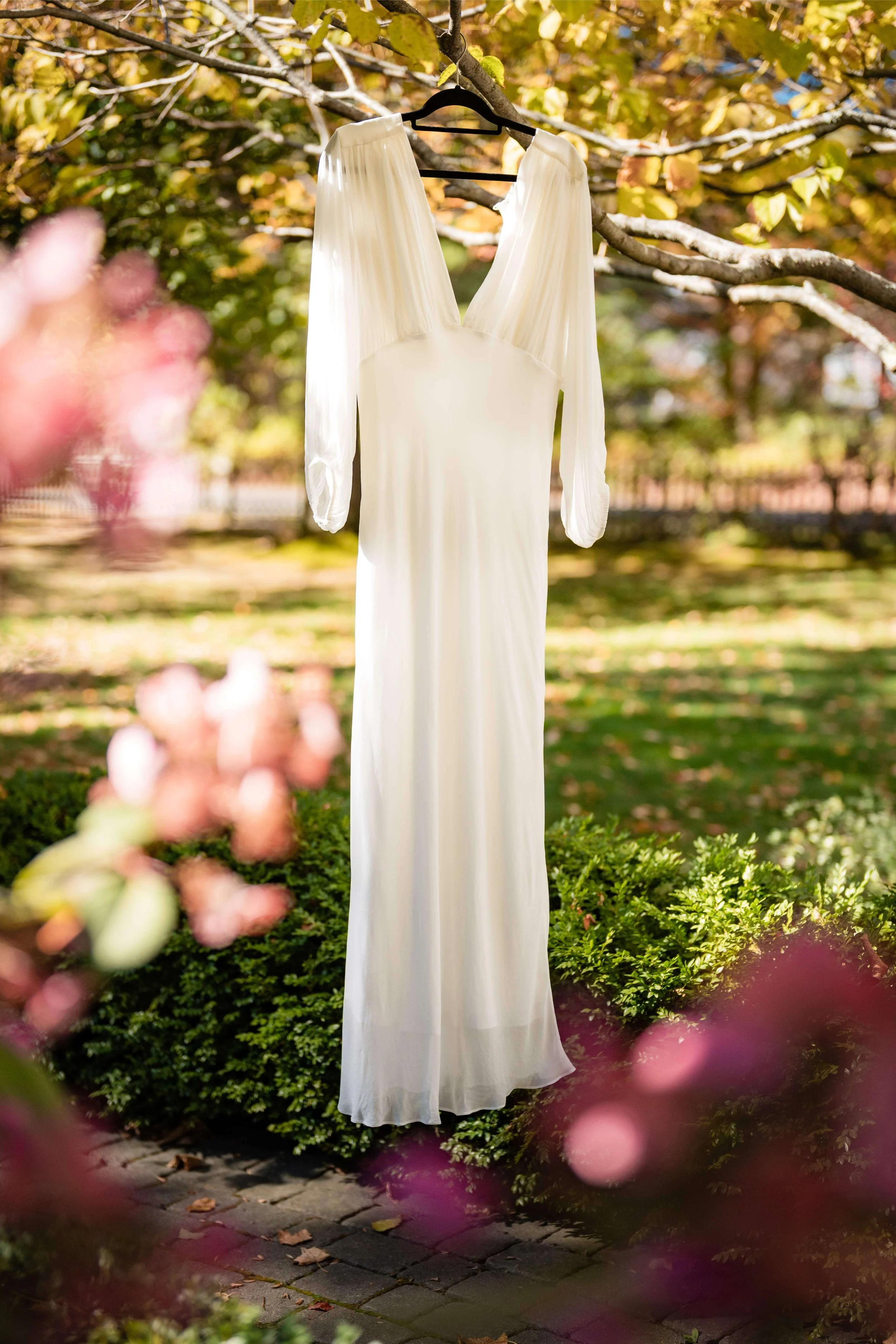 White wedding dress hanging from tree branch in sun dappled garden, North Yarmouth, Maine, wedding florals by Milkweed Floral Co