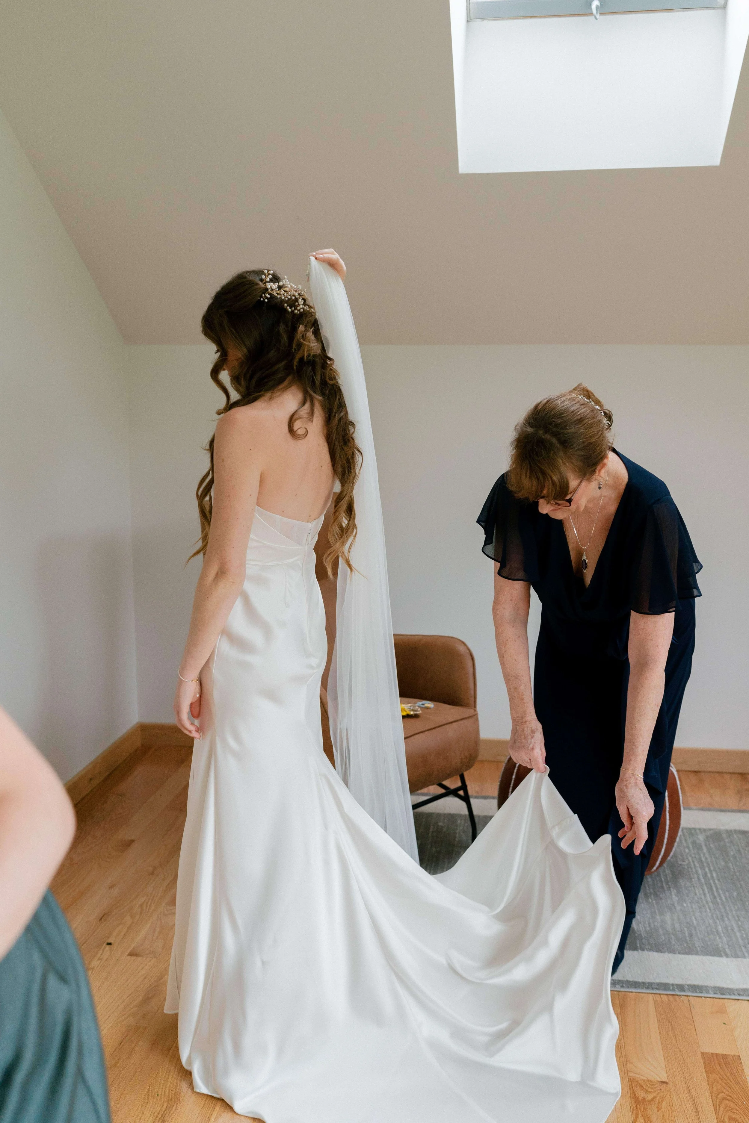 Mother of the bride adjusting the wedding dress train, bride wearing a delicate floral hair comb, getting ready detail for a New England wedding by Milkweed Floral Co