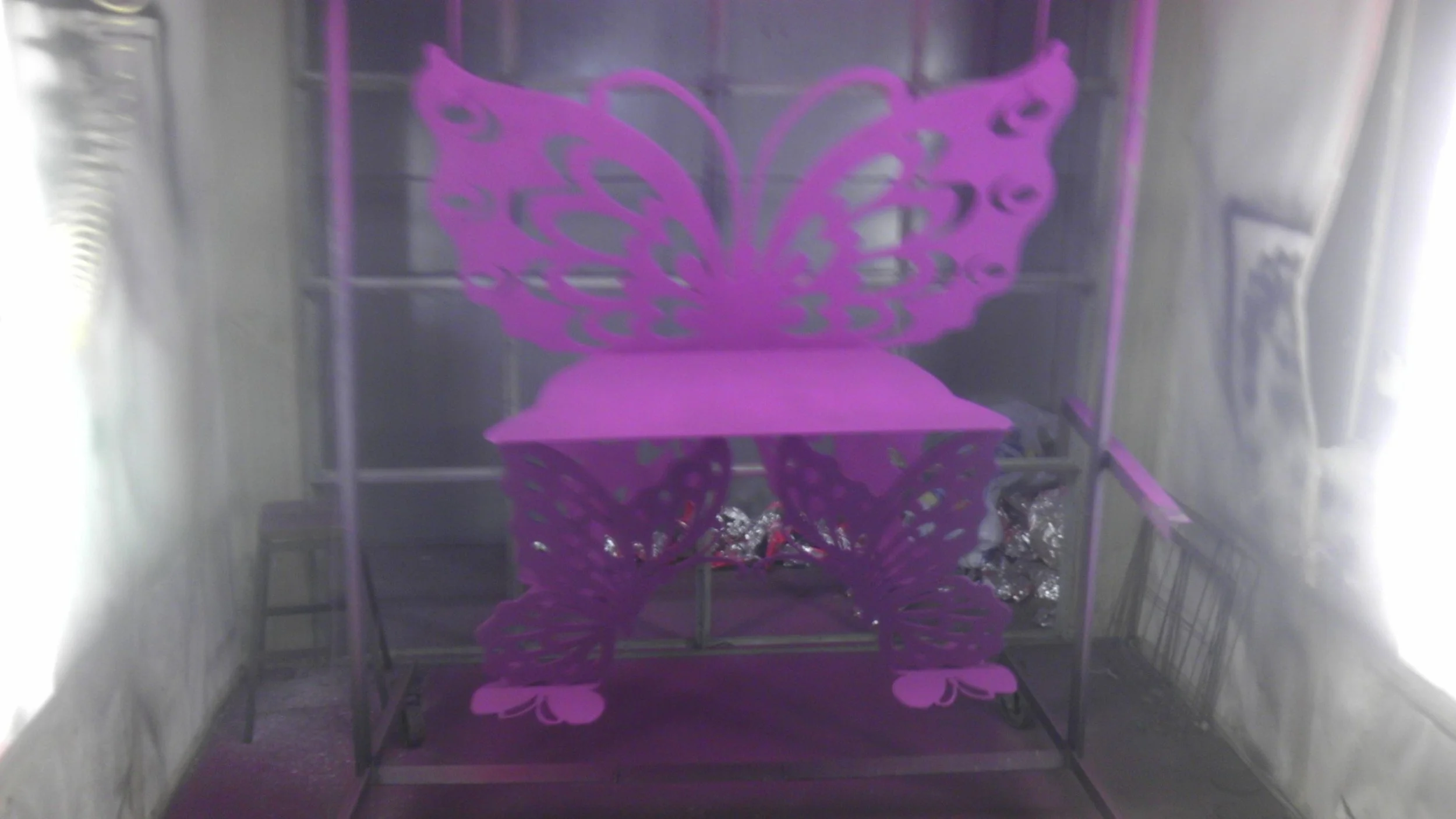 Pink butterfly-shaped paper decoration on a table in a room with reflective surfaces.