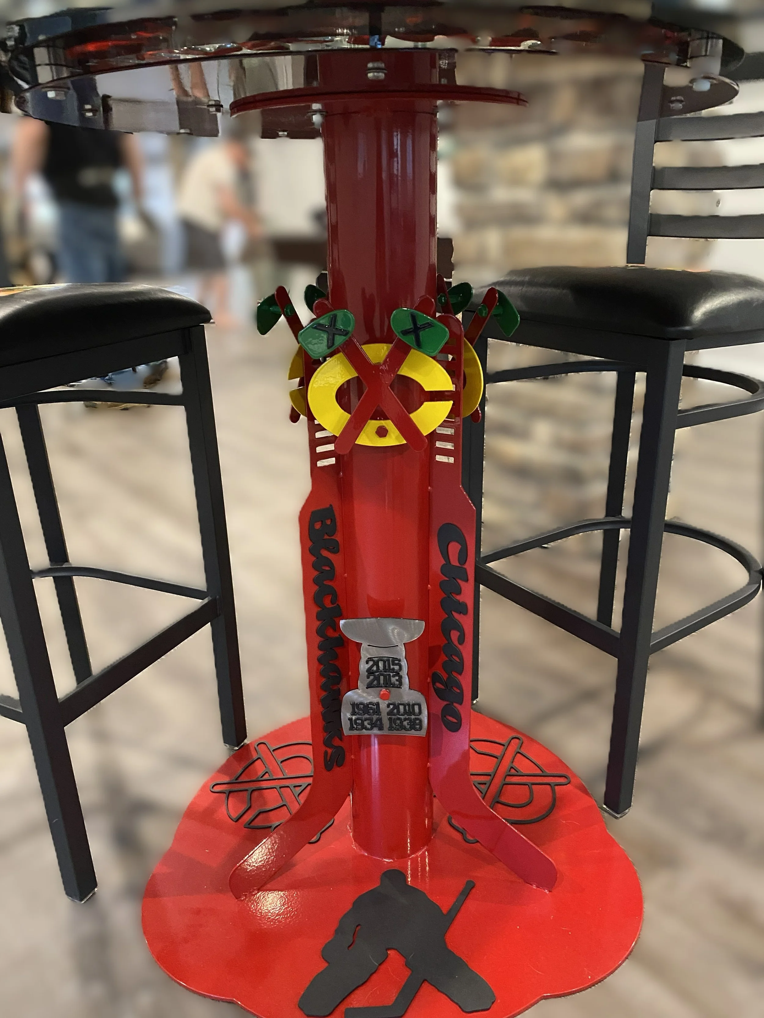 A table with a red base decorated with hockey-themed accents, including a black silhouette of a hockey player, and the words 'Blackhawks' and 'Champs'.