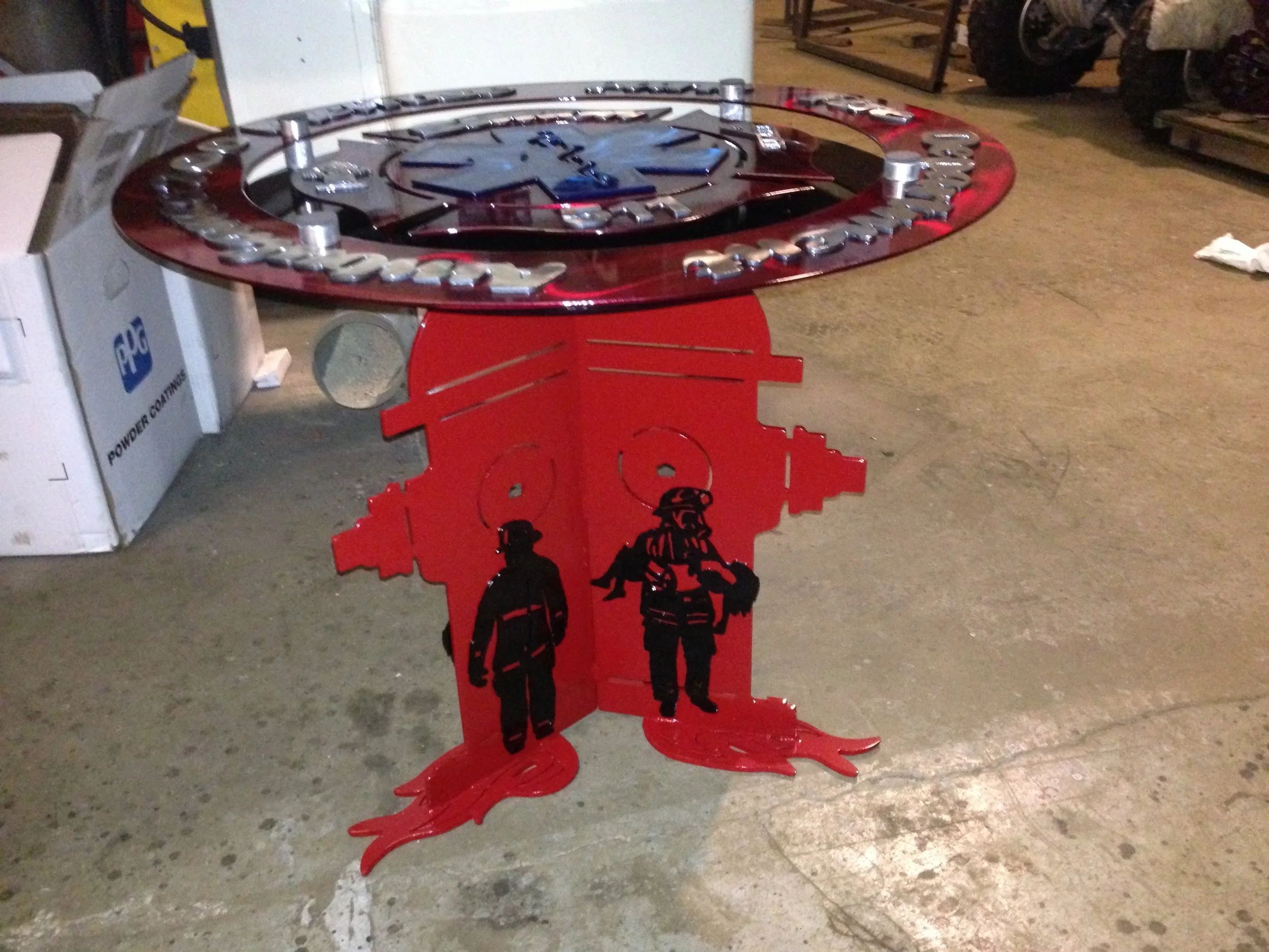 A pinball machine with a firefighter theme featuring firefighters on the base and a circular glass top.